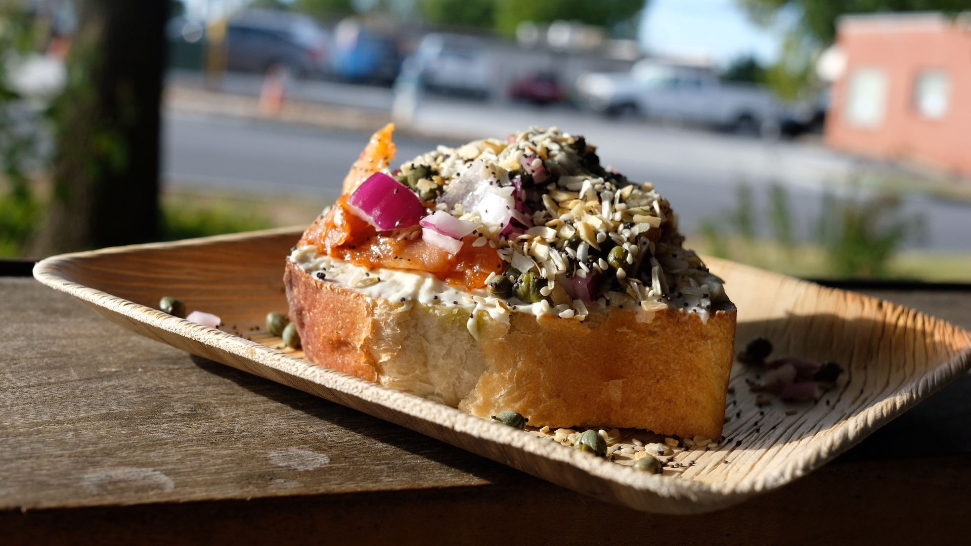 A piece of toast covered with cream cheese, lox and other ingredients.