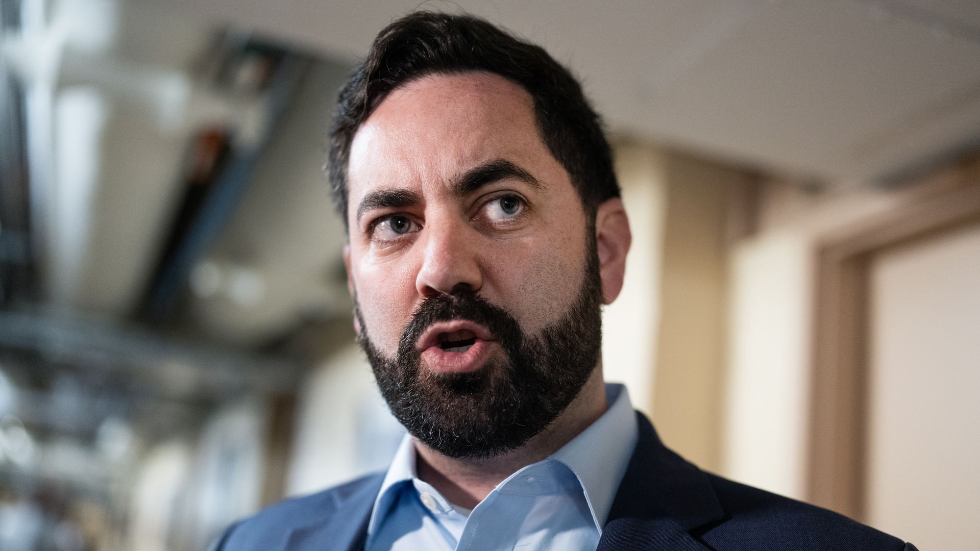 Rep. Mike Lawler, wearing a blue suit and standing in a white hallway.
