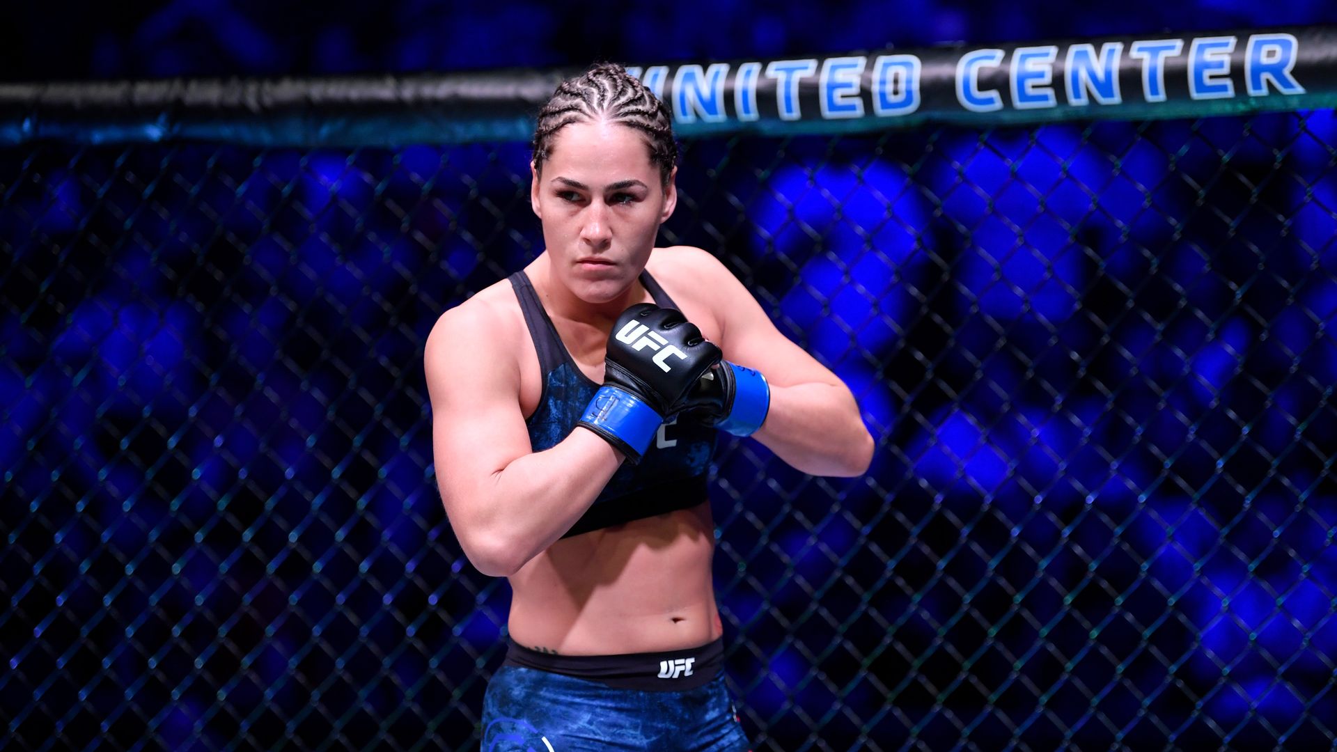 A woman dressed in blue attire gets ready to fight in the UFC Octagon. 