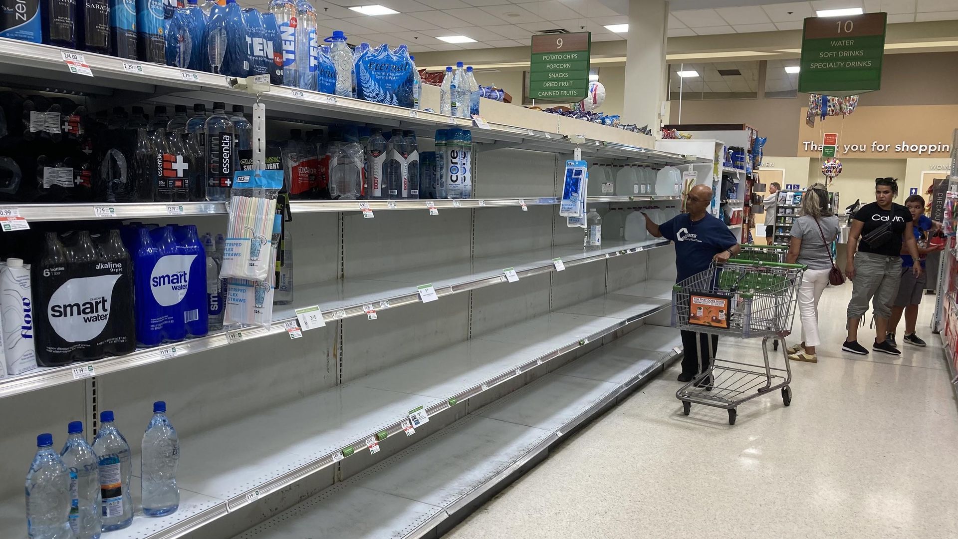 shoppers in a mostly empty aisle of water