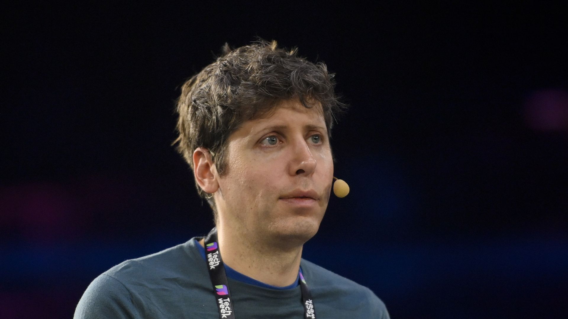 A man with a microphone on his face wearing a lanyard 