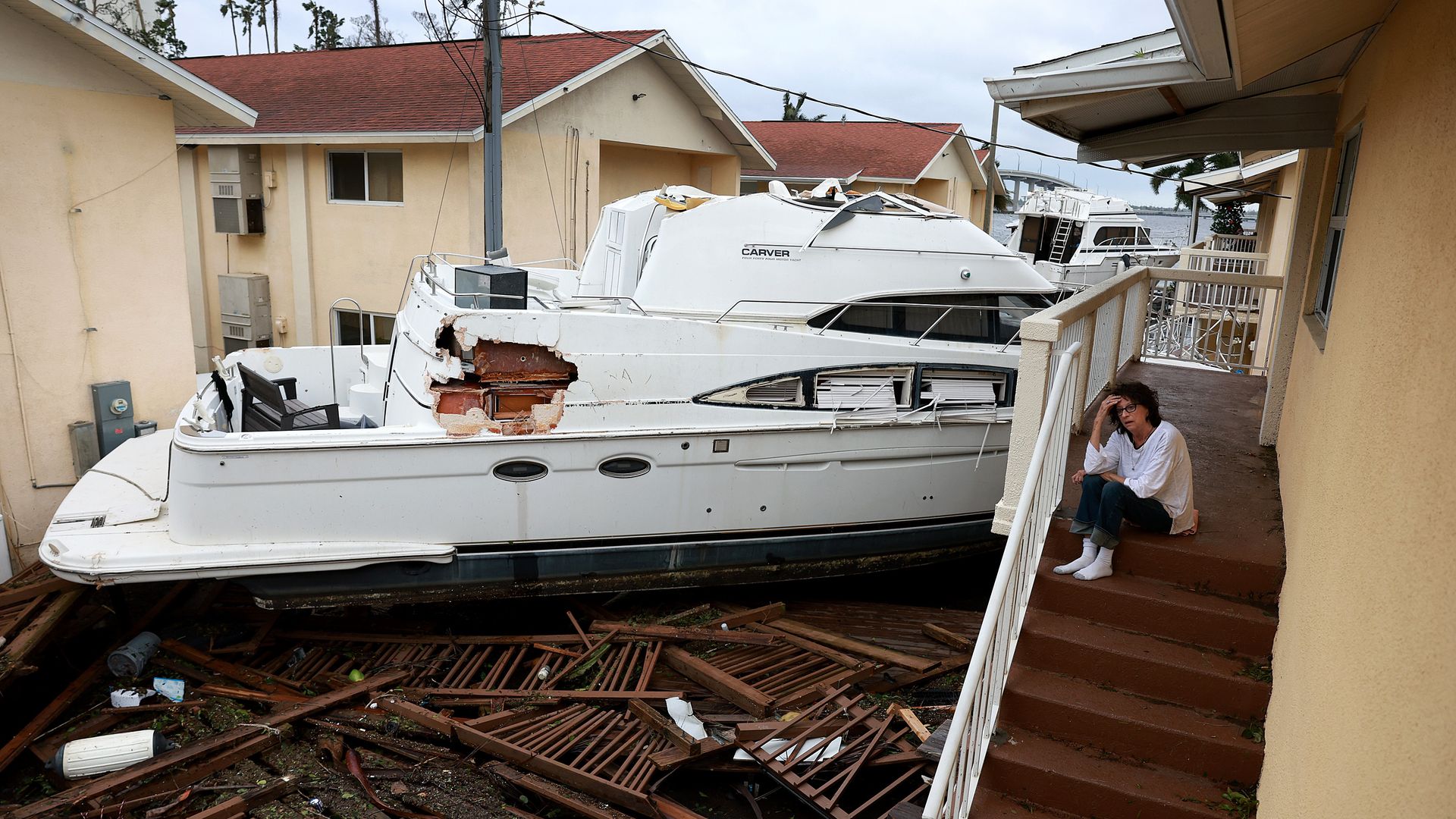 A person in Fort Myers, Florida, on Sept. 29 sitting next to a boat that crashes into a building apartment as Hurricane Ian tore through the area.