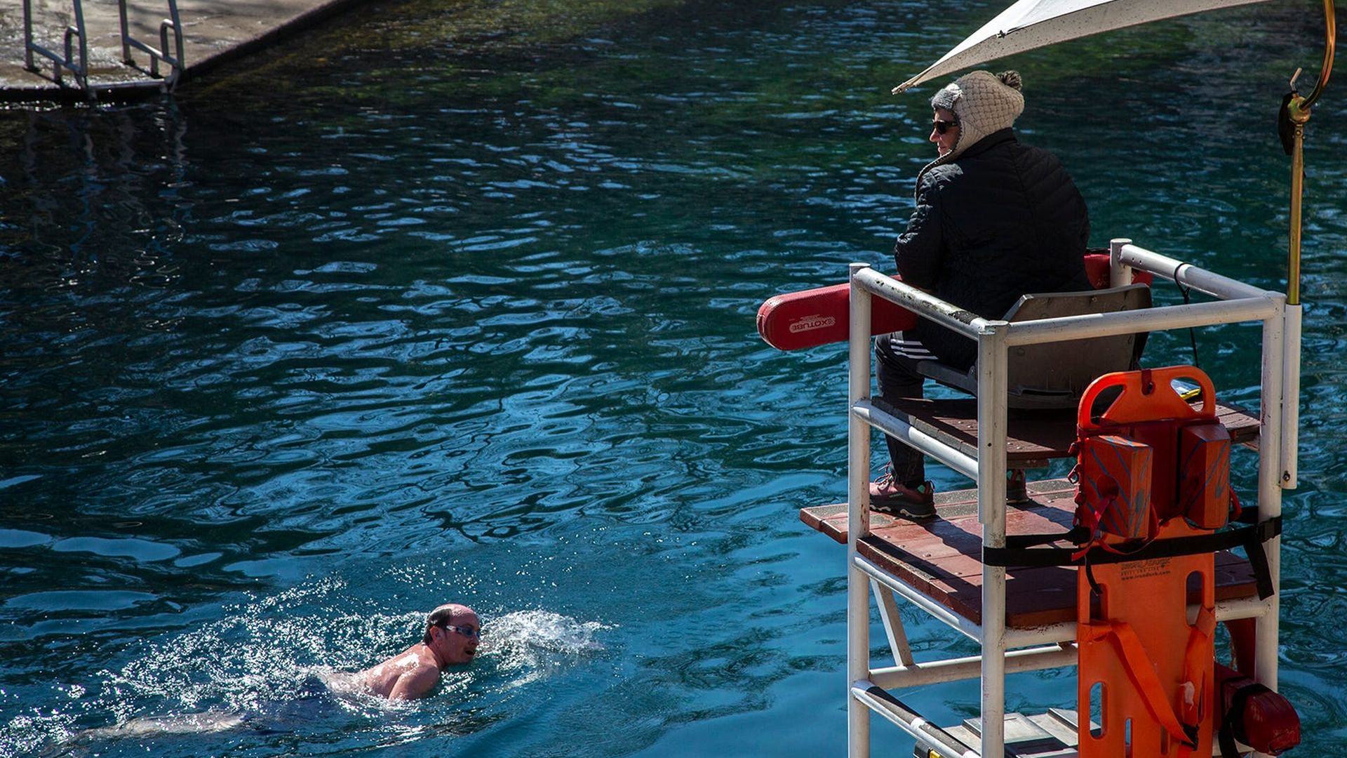 A lifeguard watches as a swimmer passes.