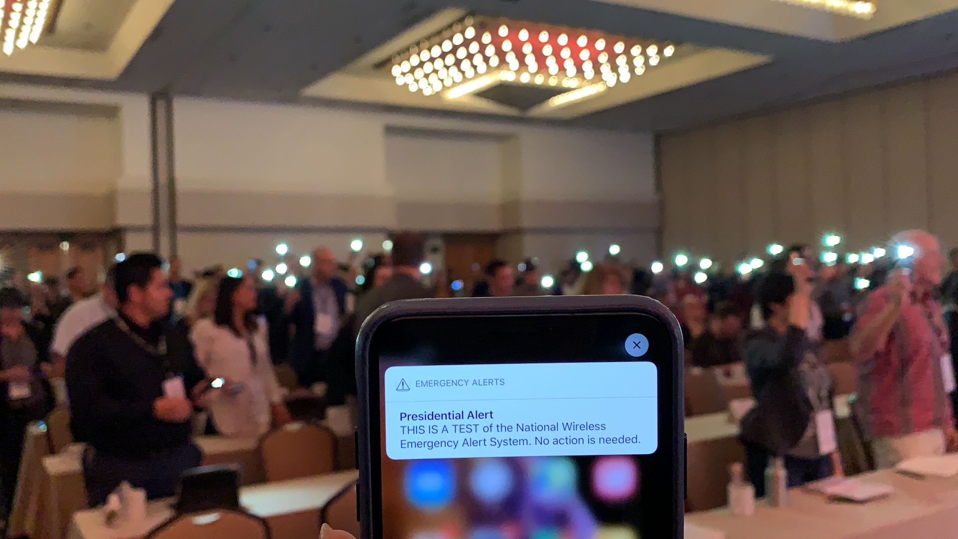 Attendees of GeekWire summit react as they receive the test Presidential Alert message