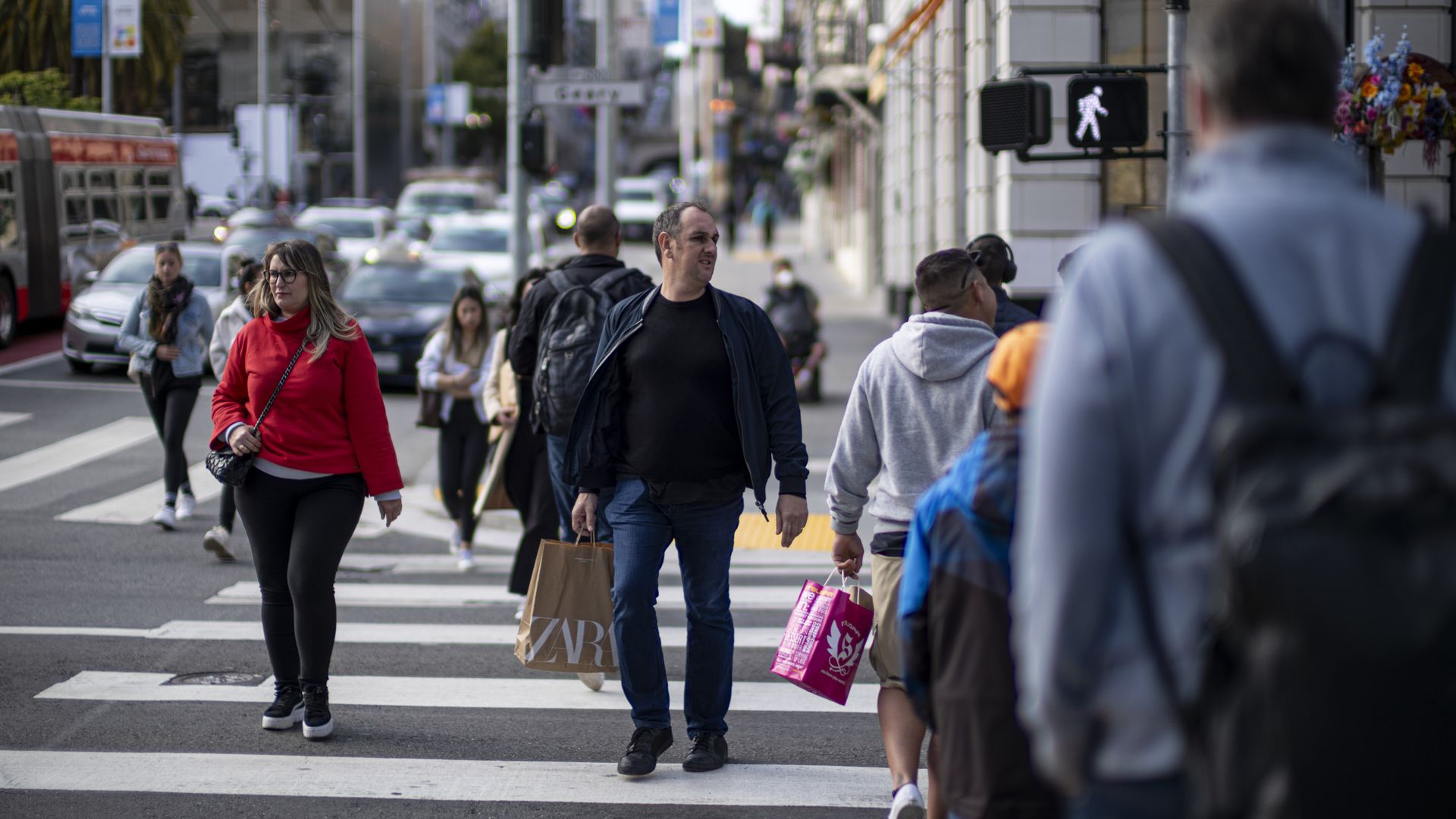 Shoppers crossing a street holding shopping bags