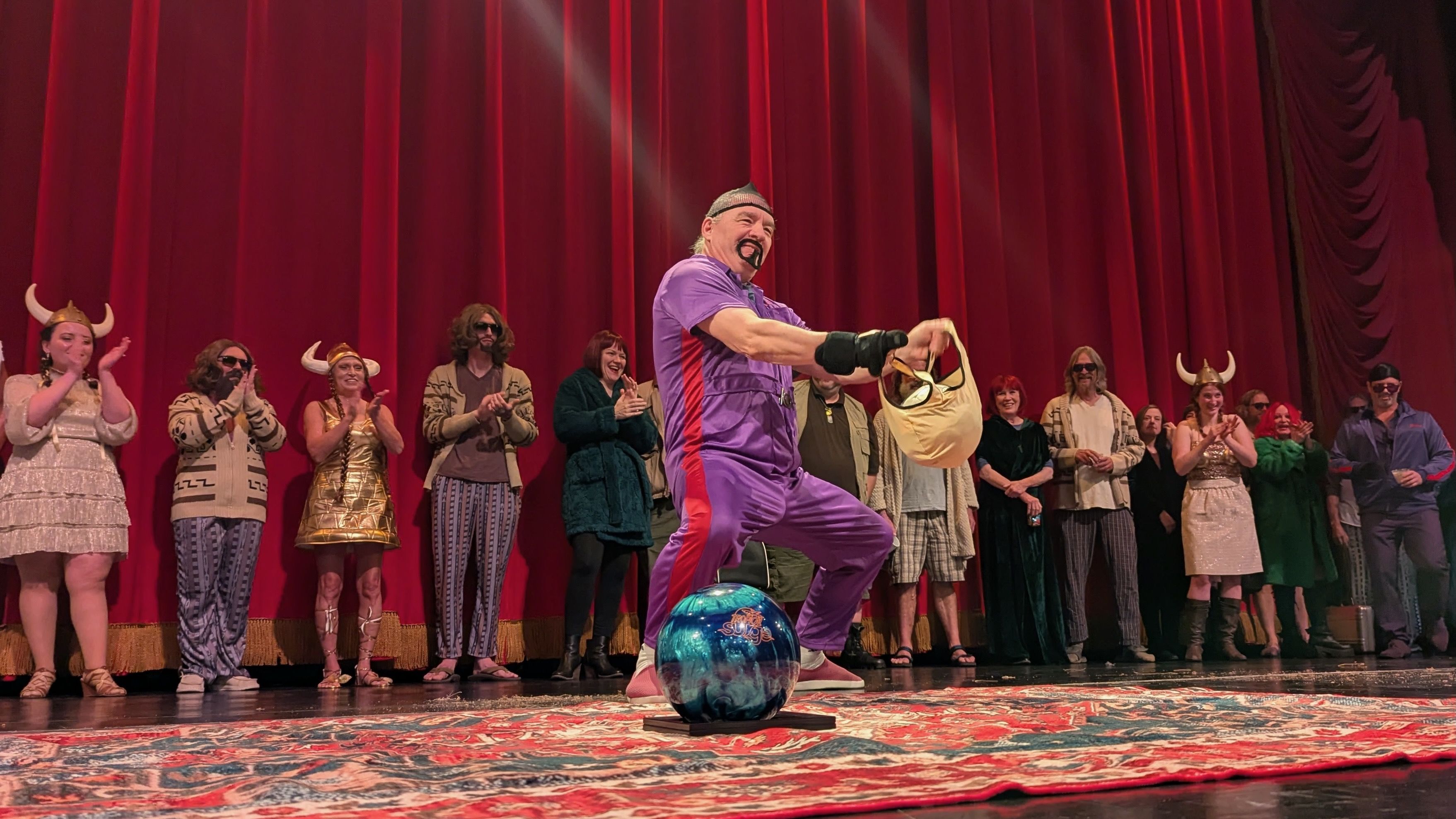 A man dressed as Jesus Quintana from The Big Lebowski polishes a bowling ball 
