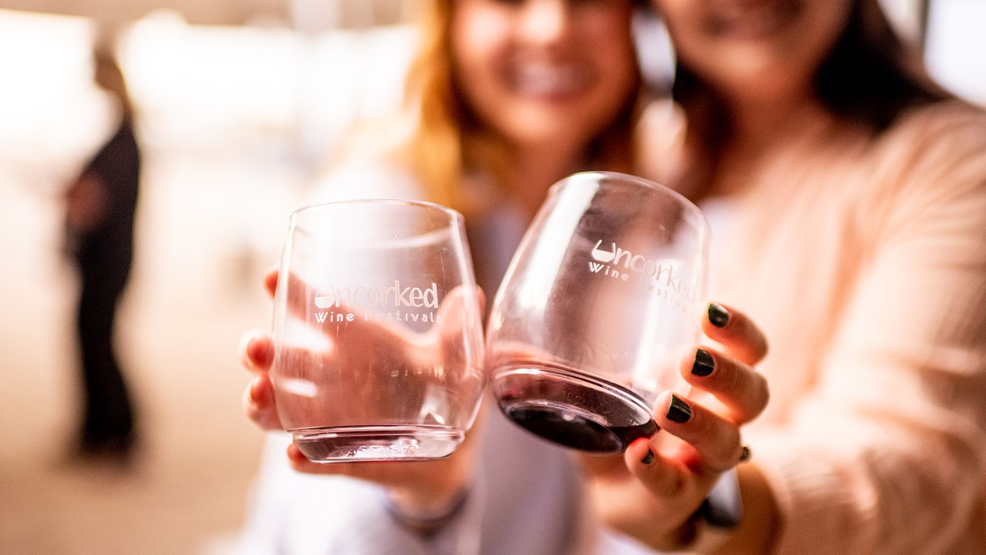 Two women holding glasses that say "Uncorked Wine Festival."