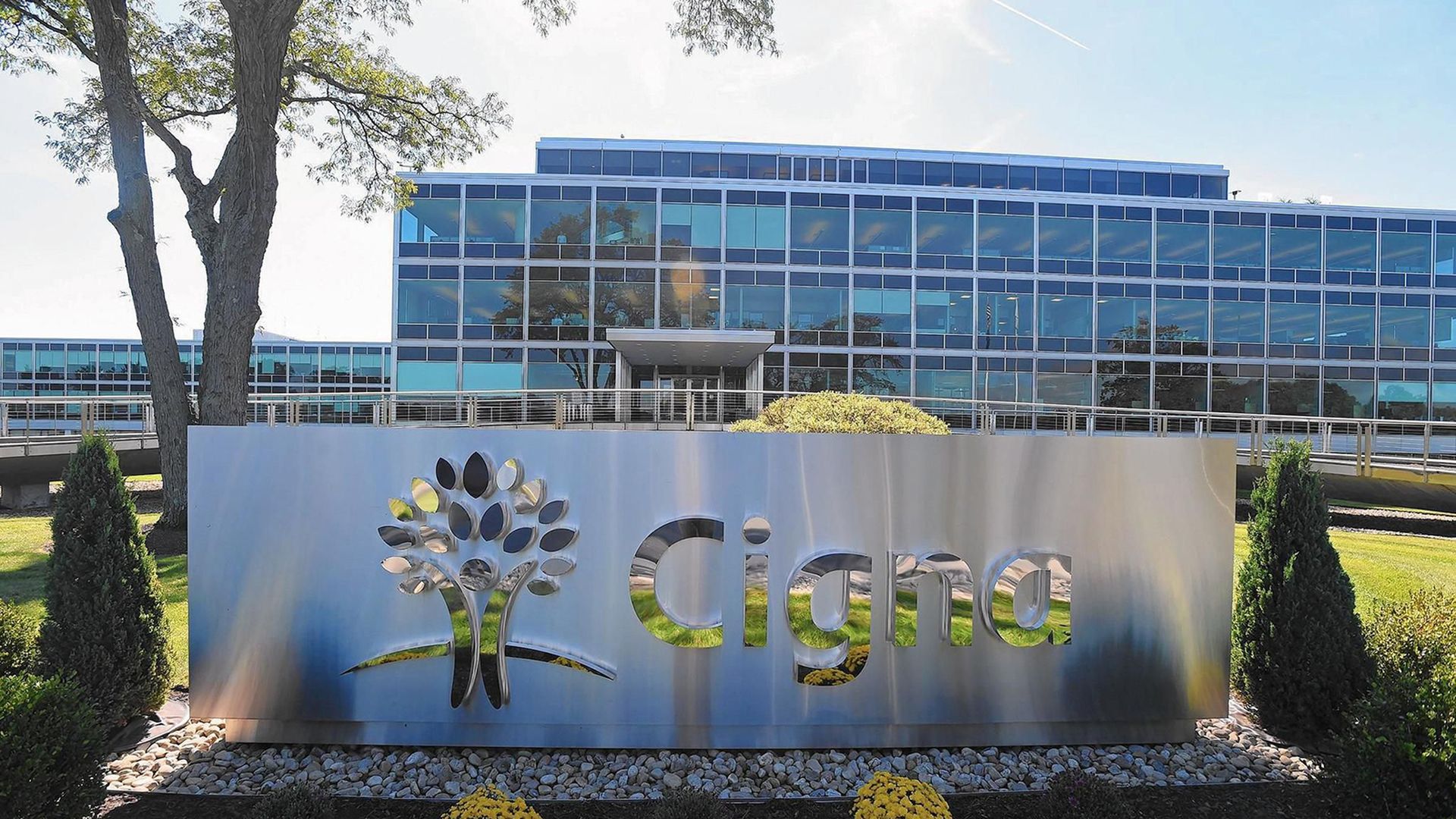 A silver sign with the Cigna logo and an office building in the background.
