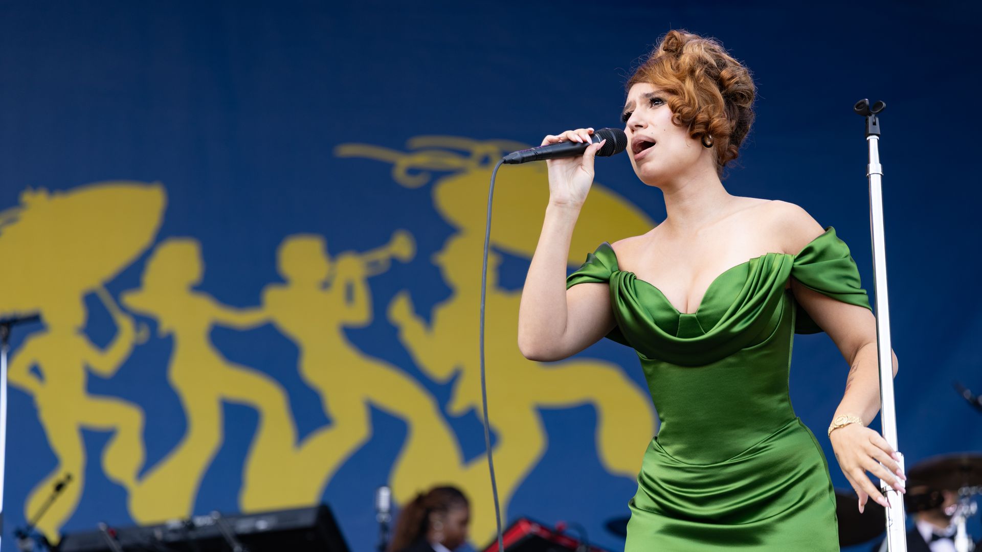 Musician Raye performs in a green dress at the 2026 New Orleans Jazz & Heritage Festival.