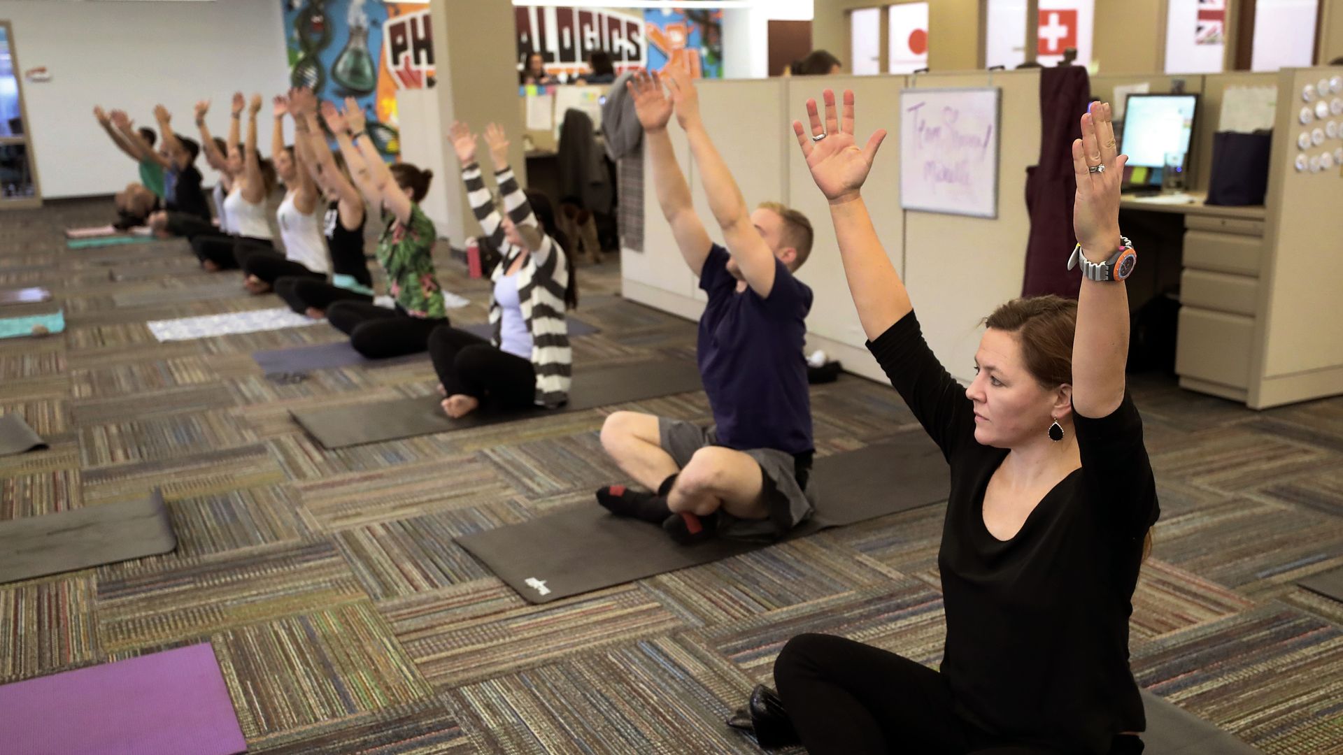 Employees practice yoga in the office.