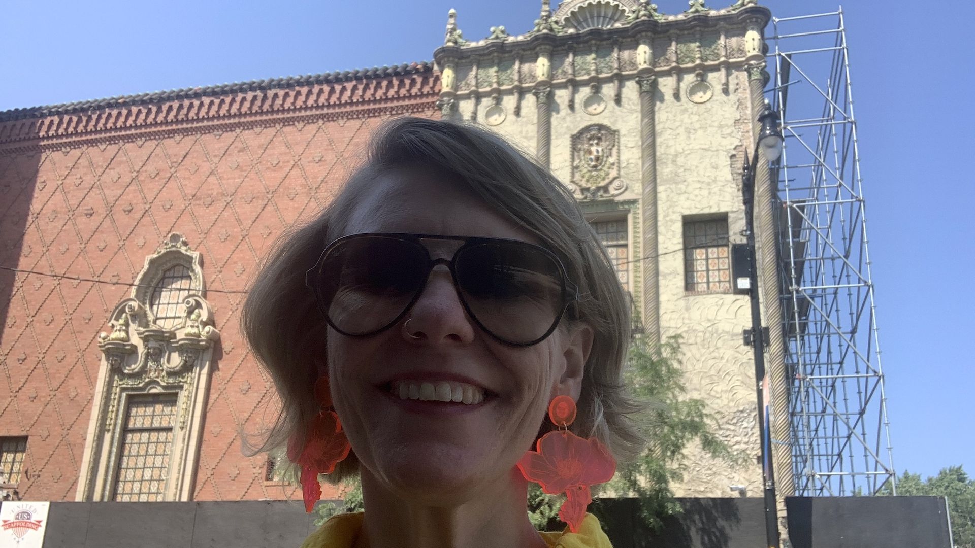 Woman in sunglasses wearing big pink earrings in front of a Moorish style theater.
