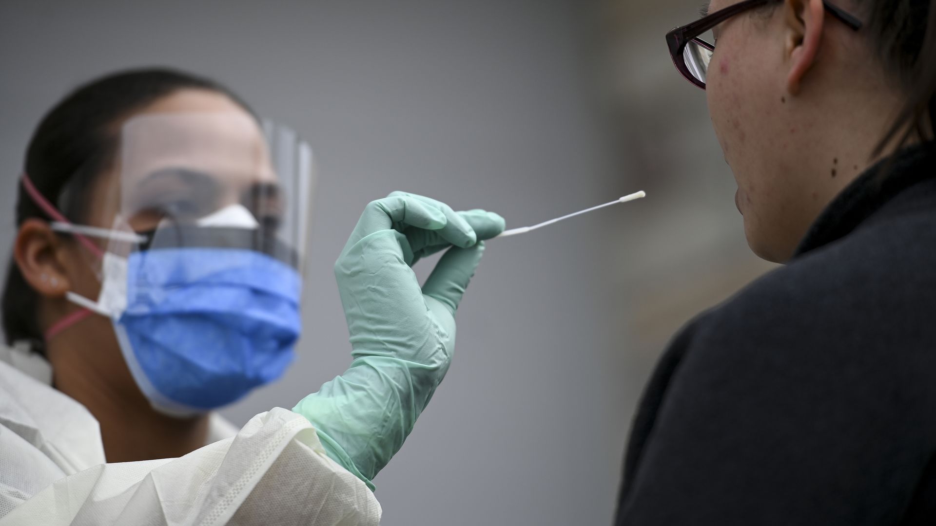 A doctor wearing a face mask swabs a patent for a coronavirus test.