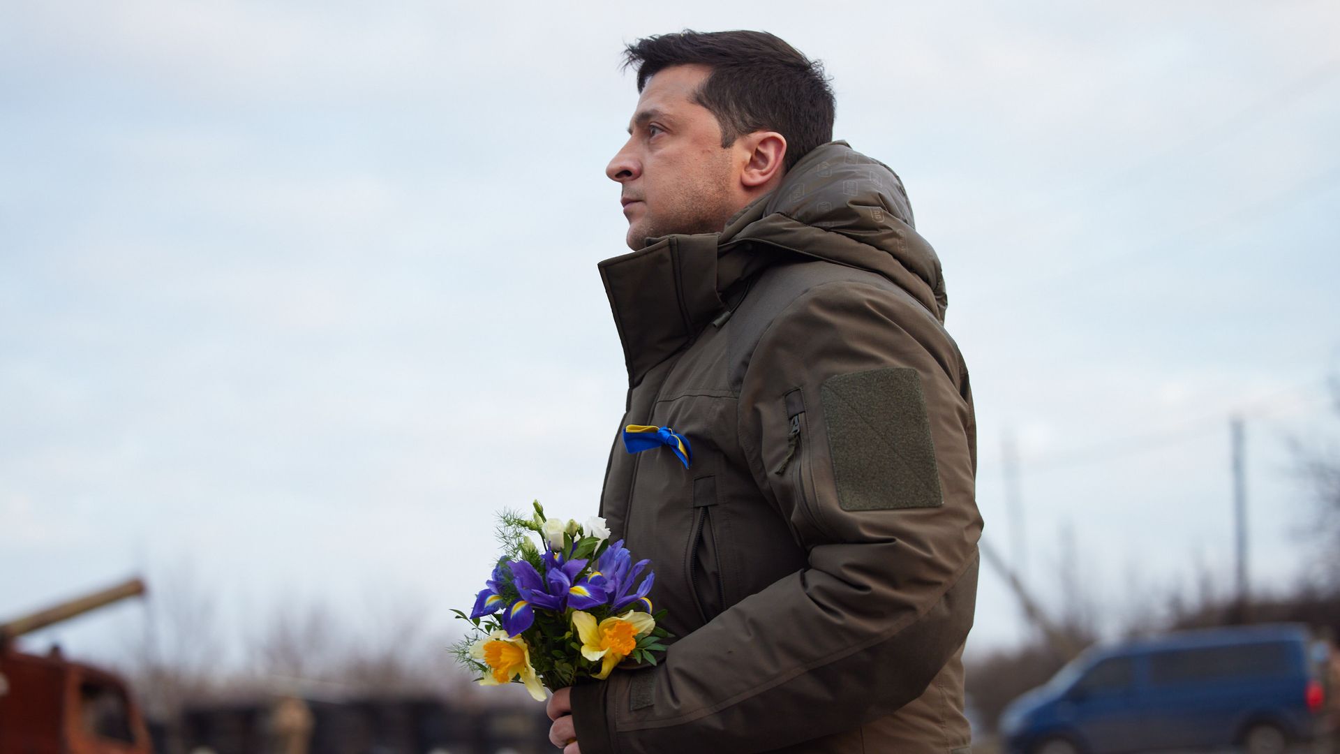 Photo of Volodymyr Zelensky standing with purple flowers in his hands