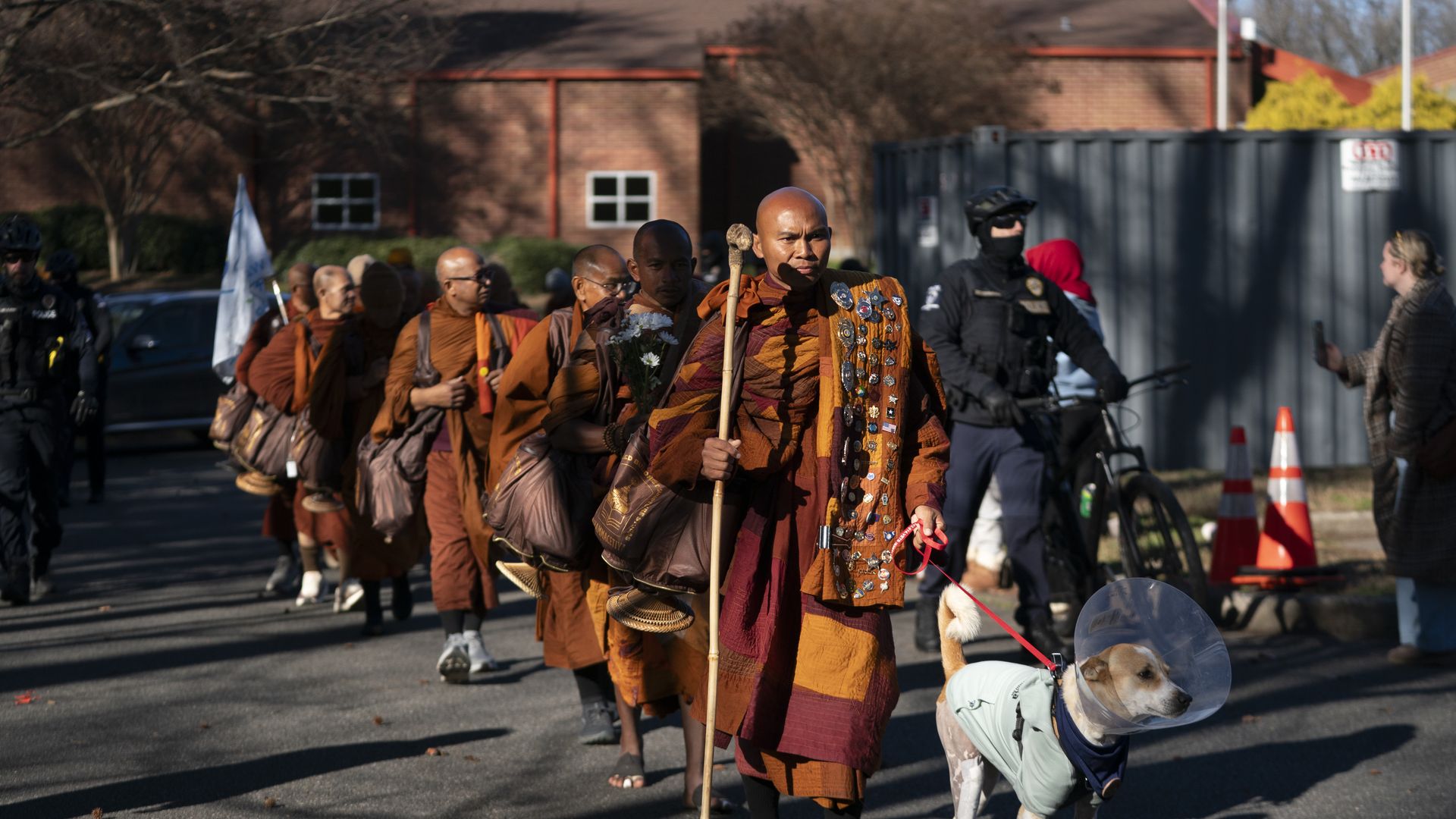 A group of monks walking with a dog in the front