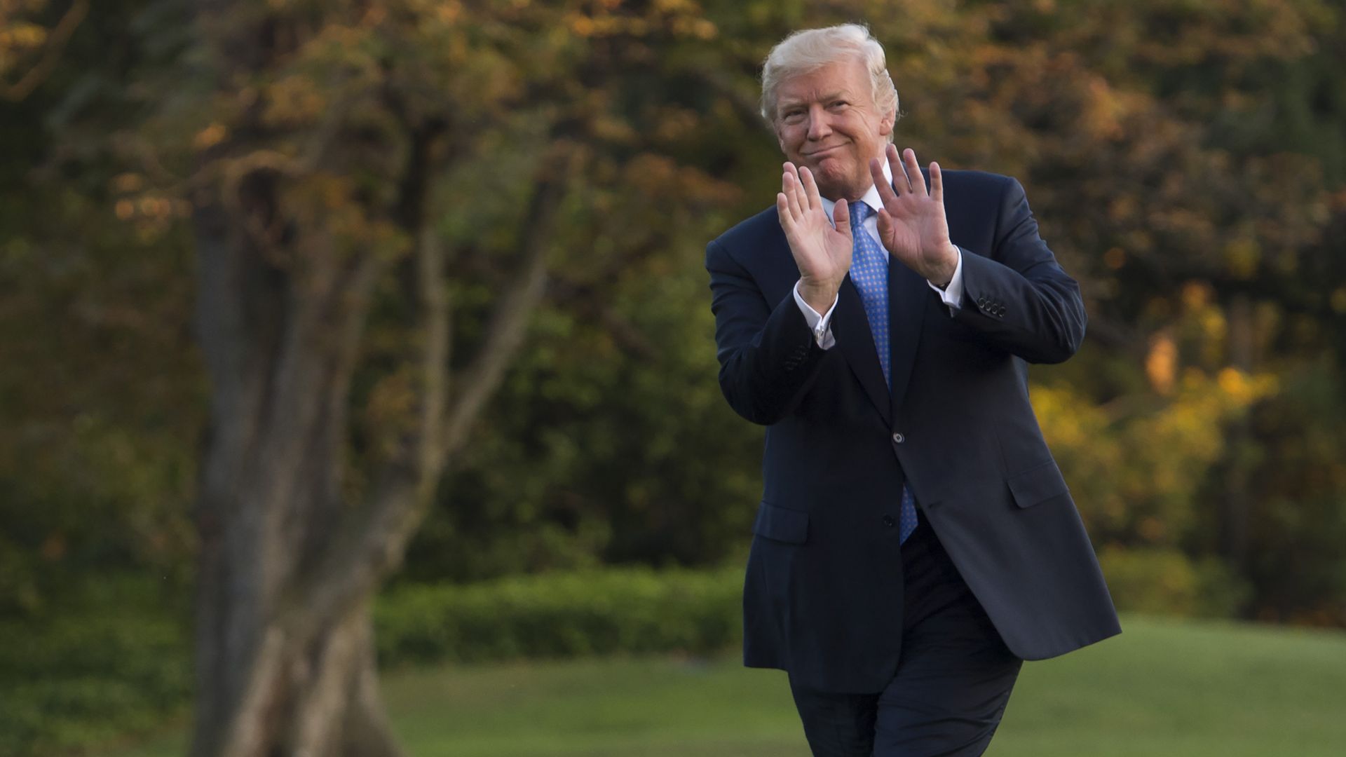 President Trump walking on the lawn with his hands up