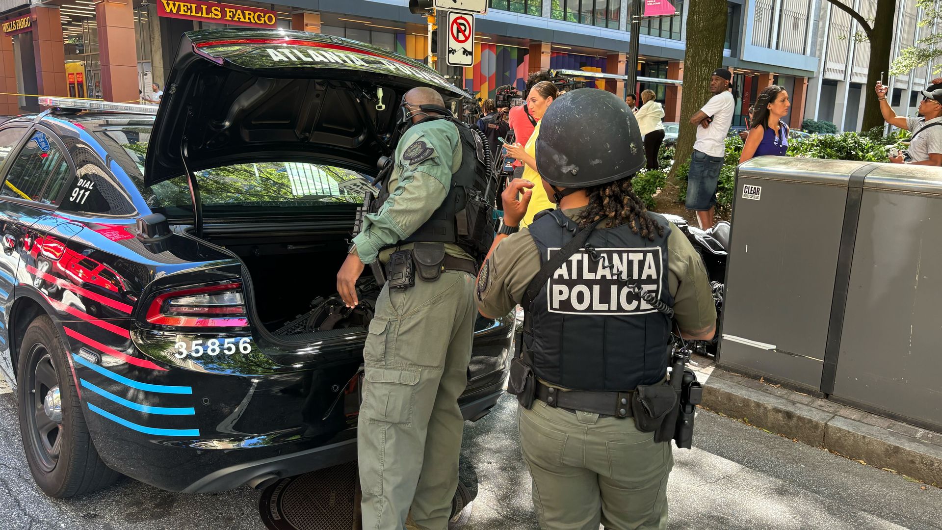 Police in tactical gear with "Atlanta Police" on their vests get equipment from their trunk