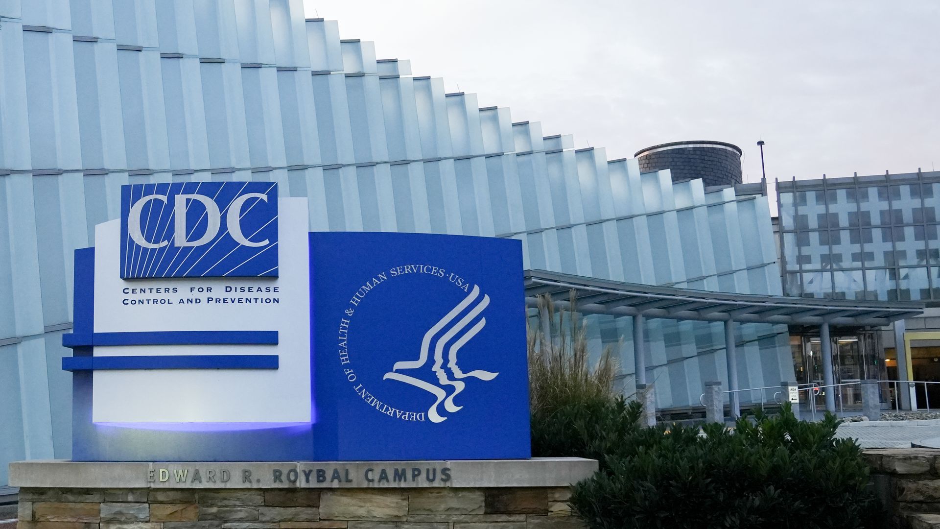 CDC sign in front of glass building on a cloudy day.