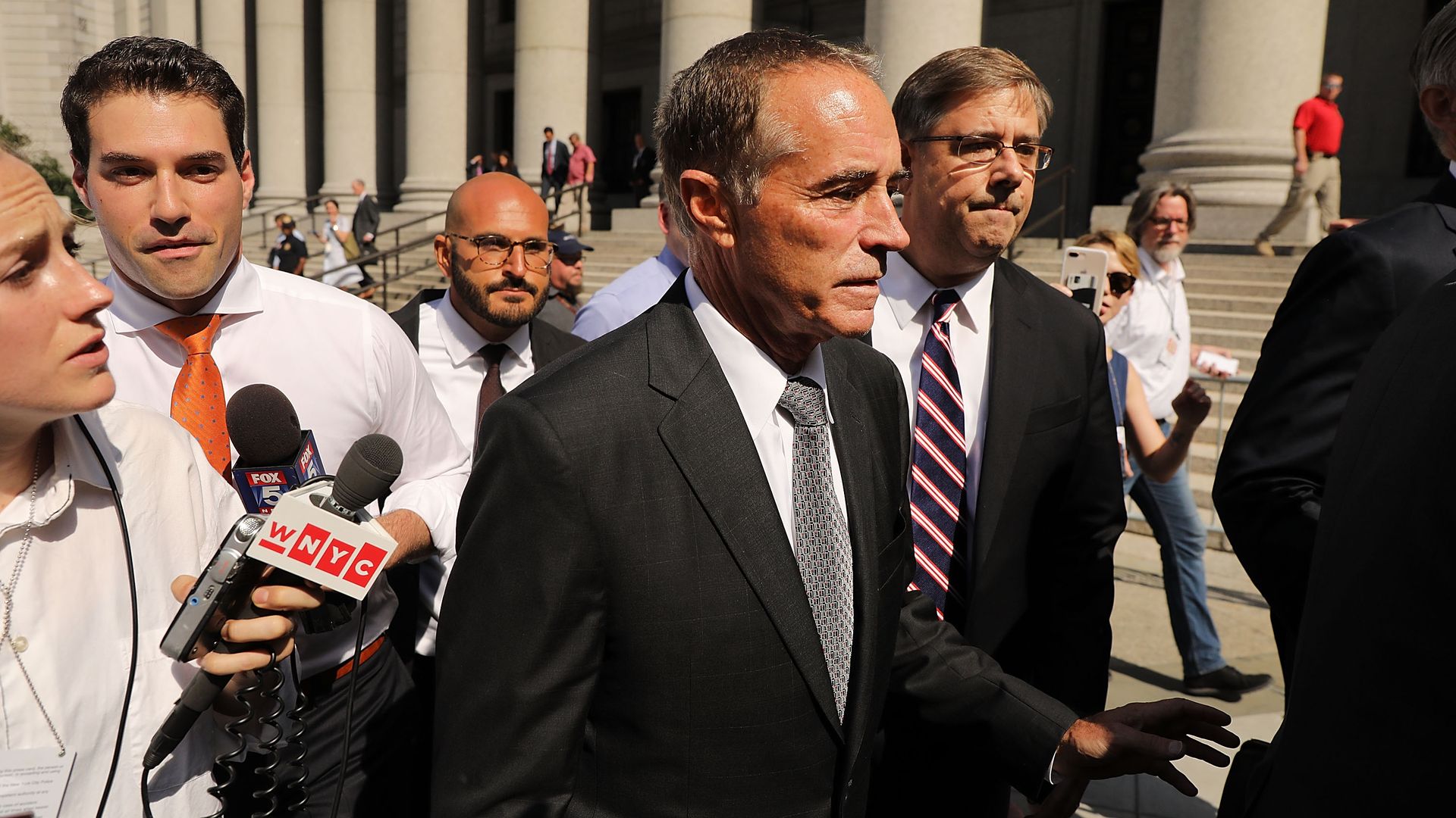 Chris collins outside of the DC courthouse in a black suit surrounded by reporters during the day.