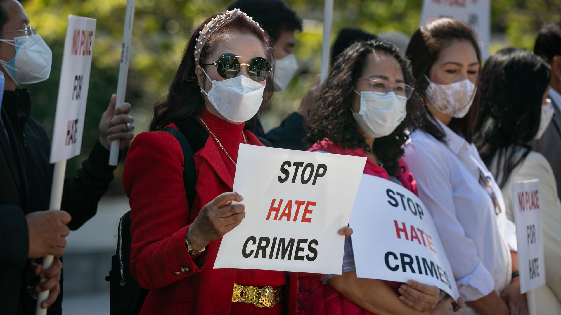 Picture of a woman holding a sign that says "Stop Hate Crimes"