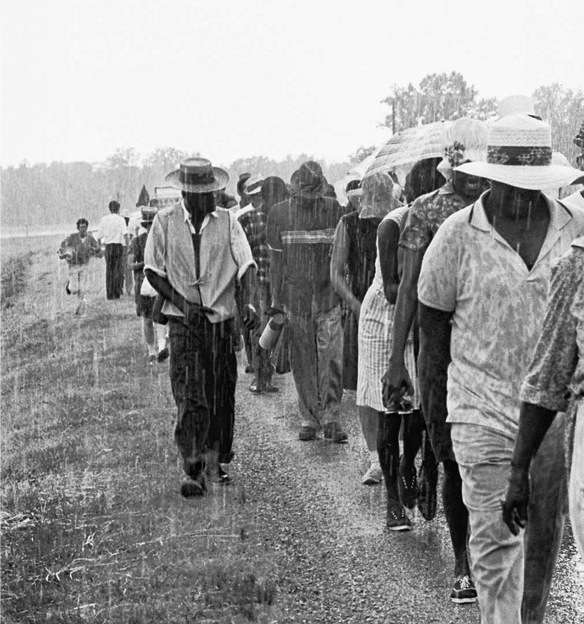 Black protestors march in Mississippi in the 1960s in the rain.