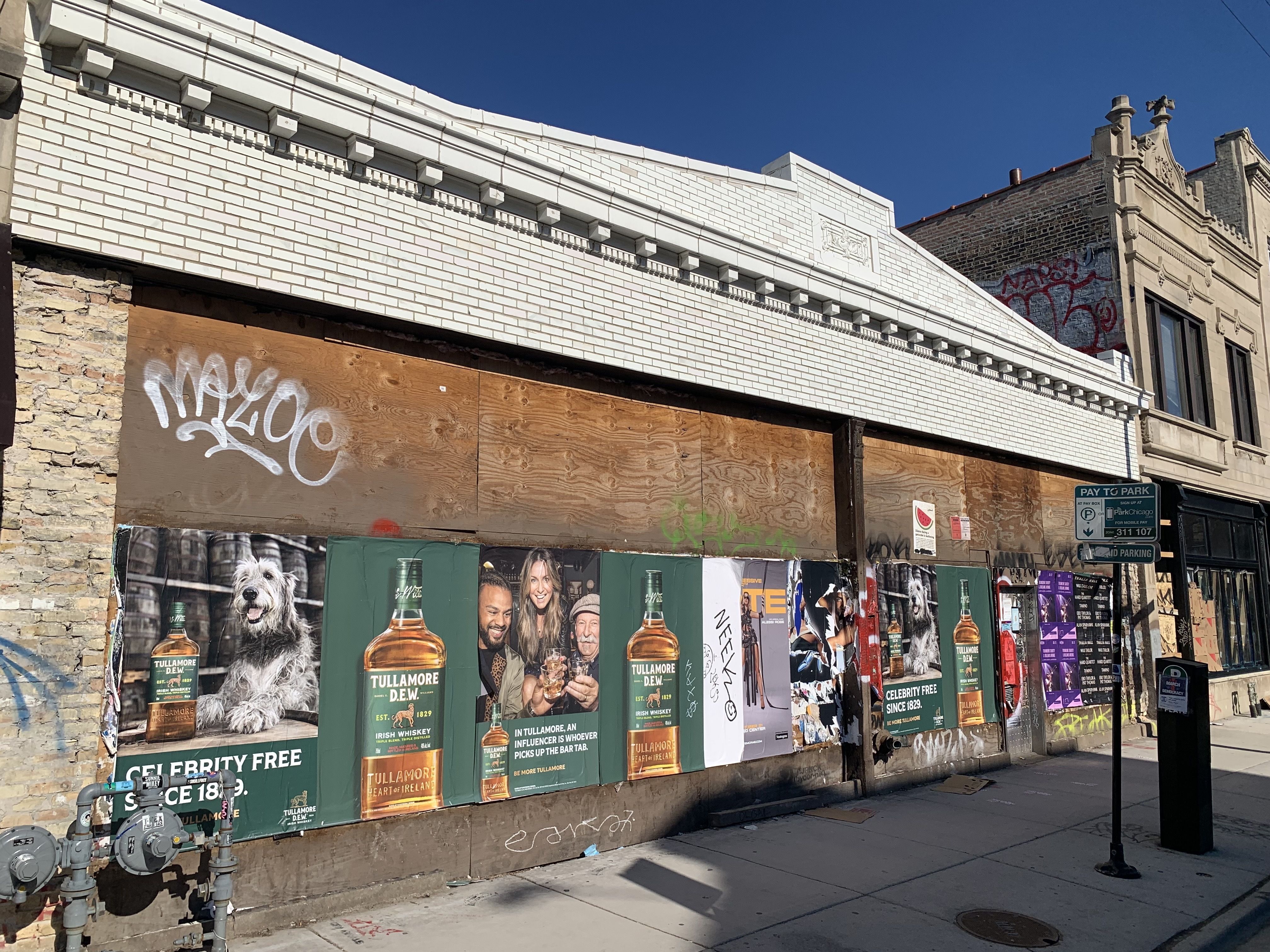Photo of a boarded up storefront with graffiti and posters.
