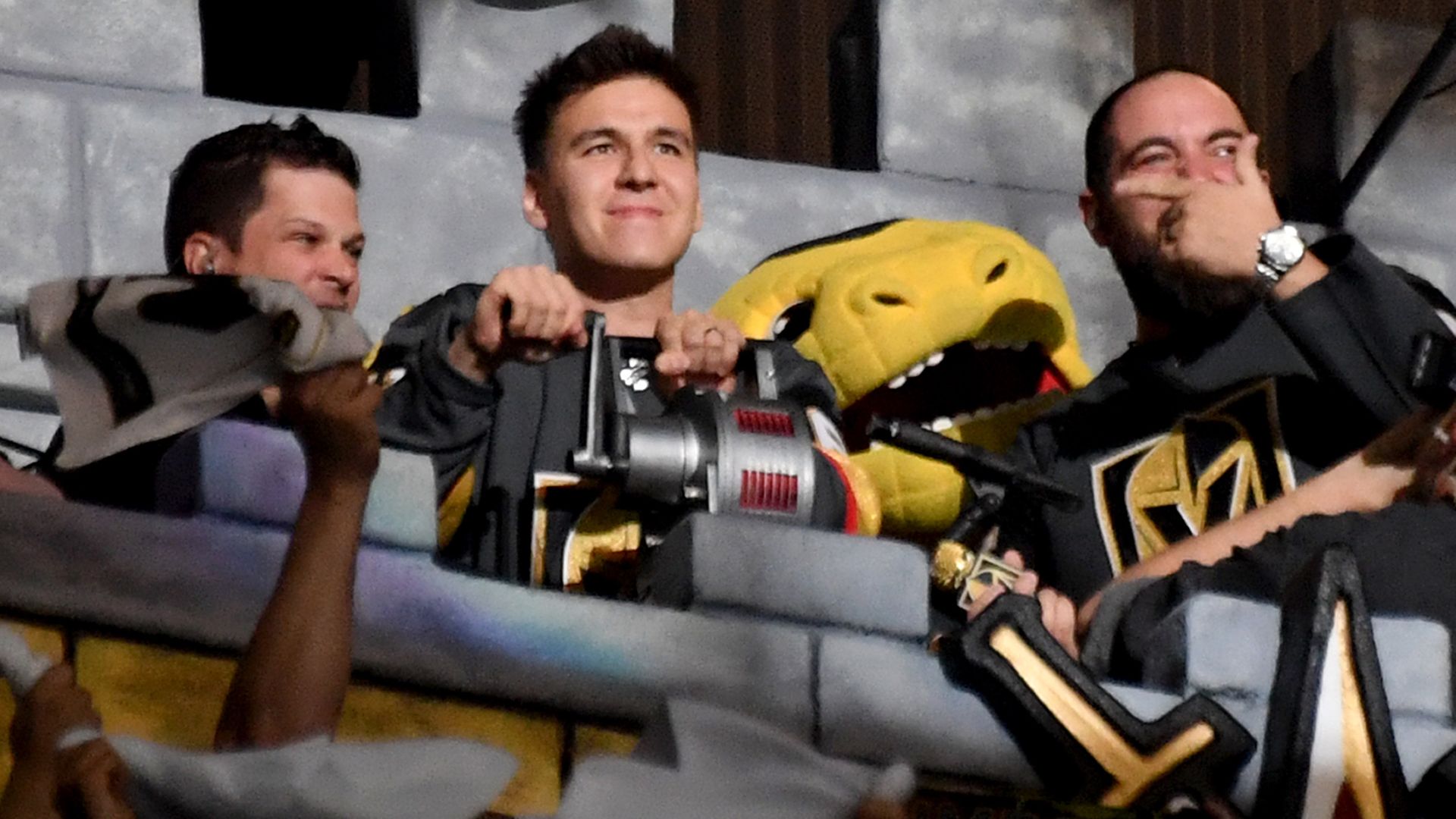 In this image, James Holzhauer sits between two other men at a sports game.