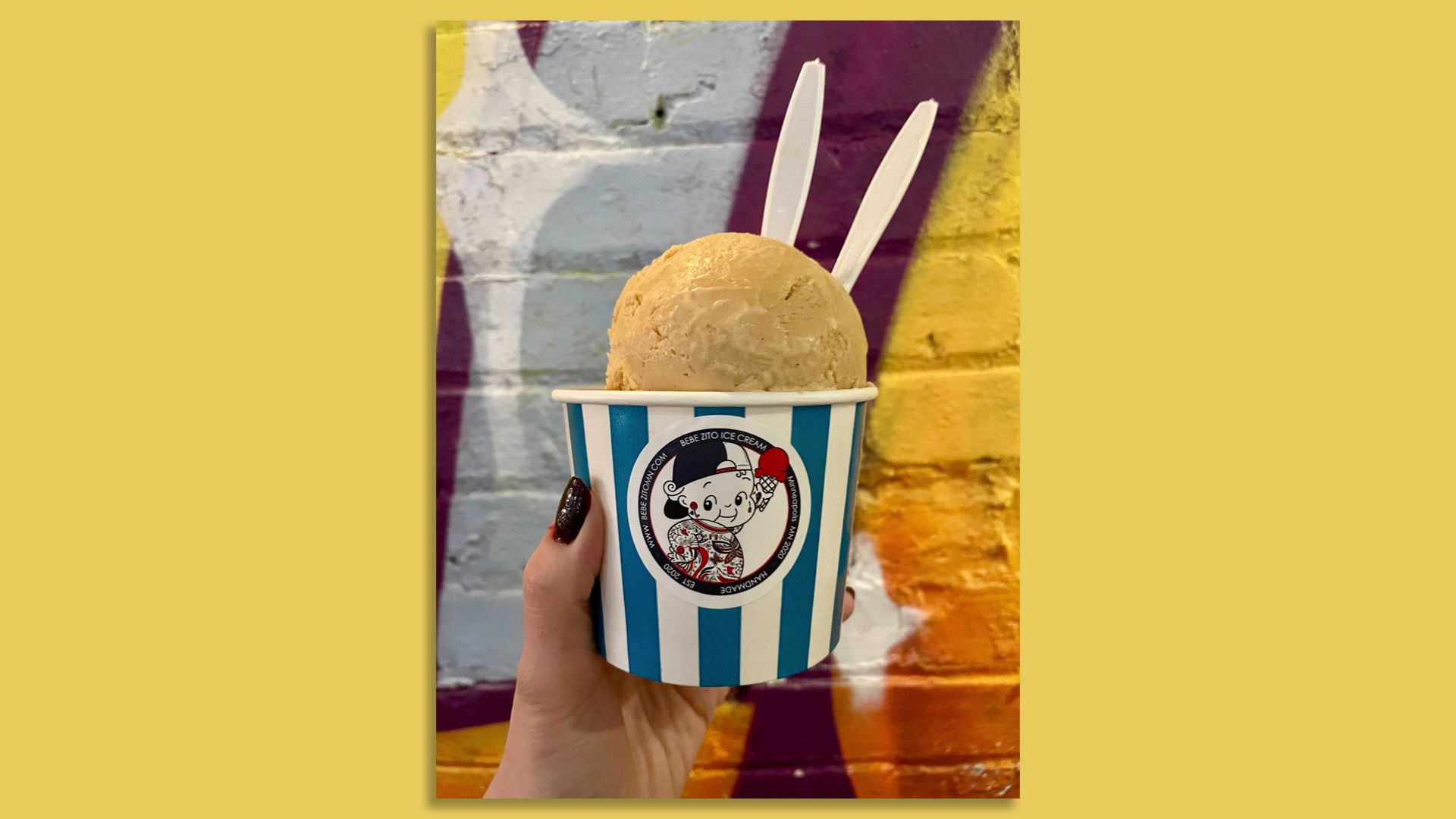 two scoops of ice cream in colorful striped cup in front of graffiti background