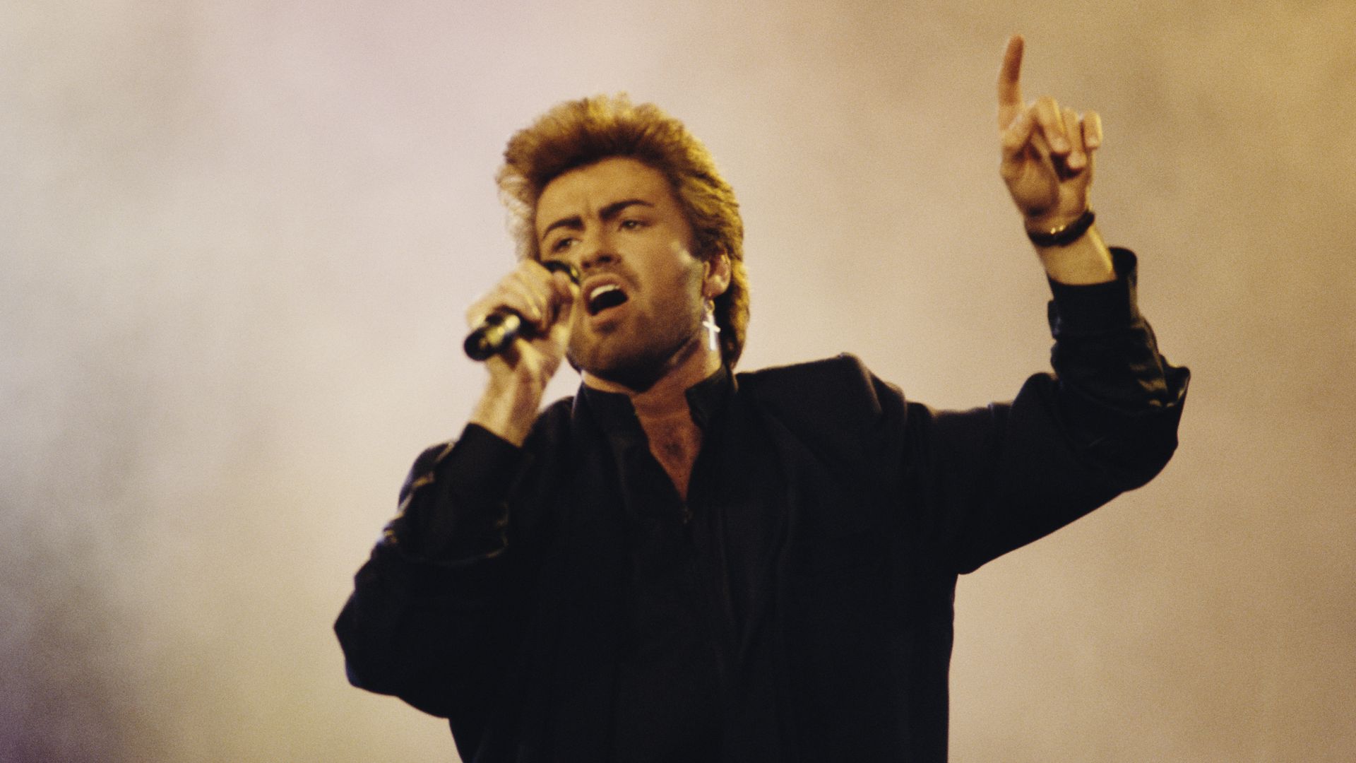 Singer George Michael sings into a microphone. 