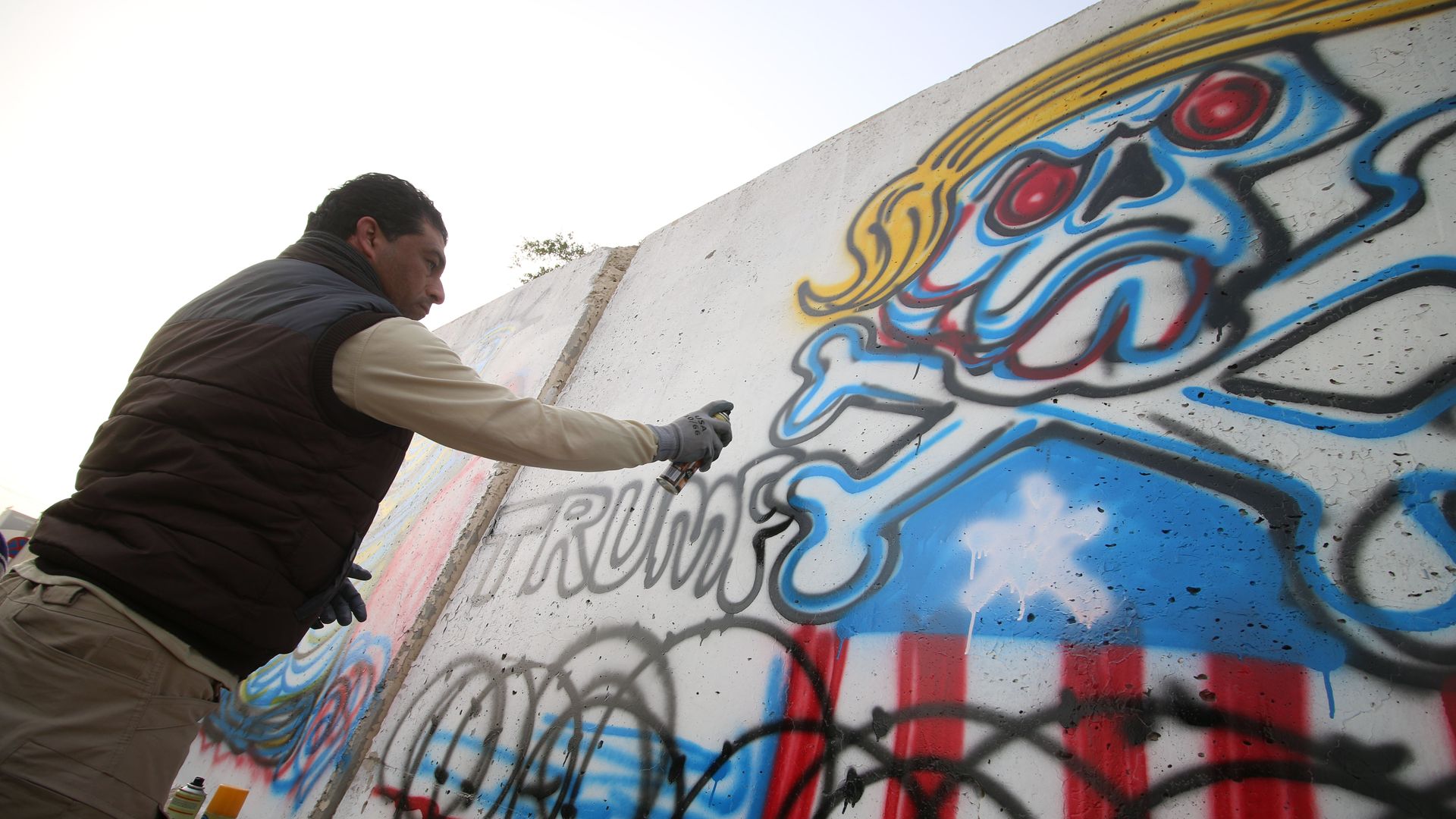 An Iraqi graffiti artist sprays a cement wall with anti-US President Donald Trump slogans in the southern Iraqi city of Basra on February 2, 2017.