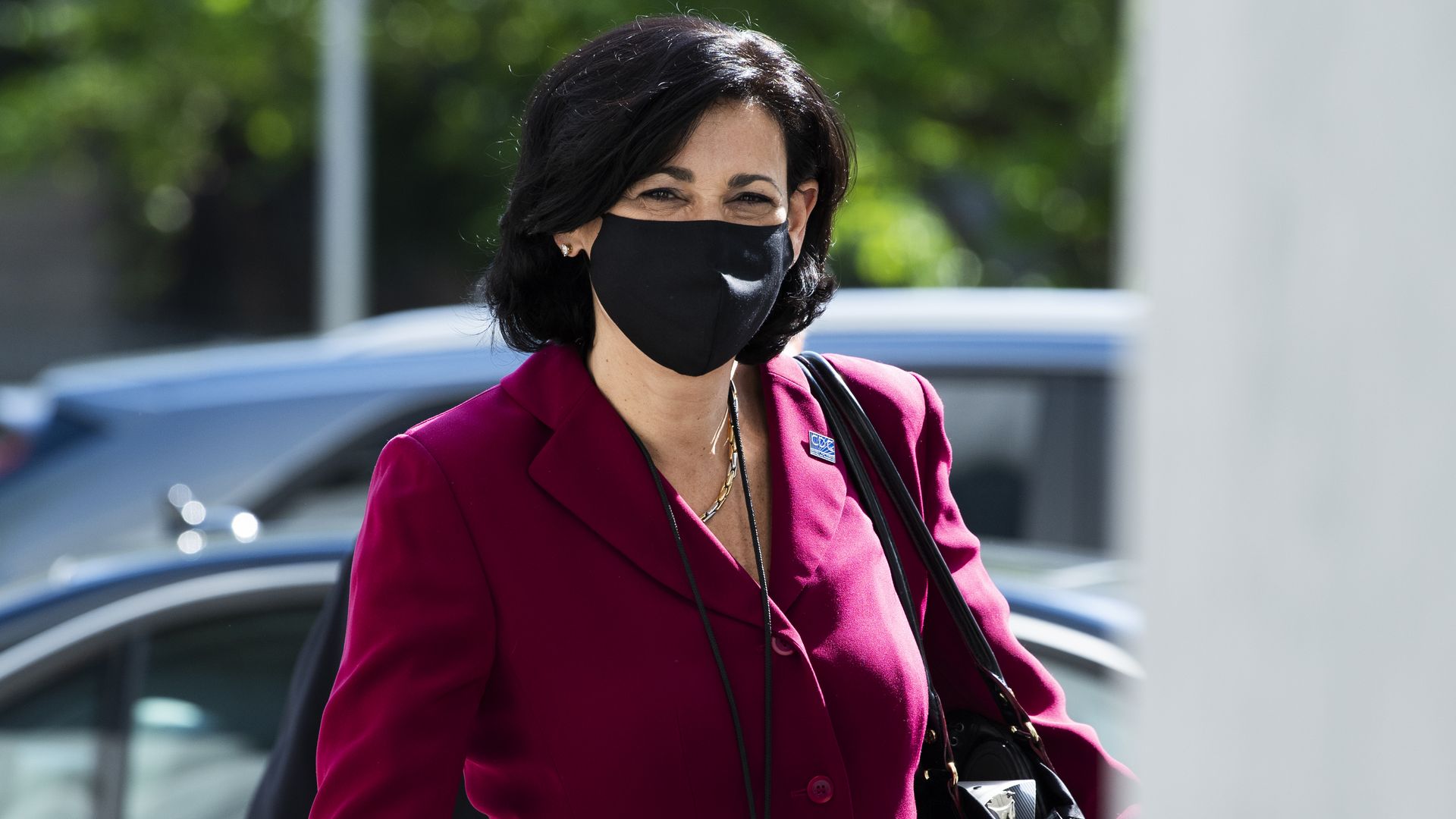 Rochelle Walensky walks outside wearing a black mask on her face.