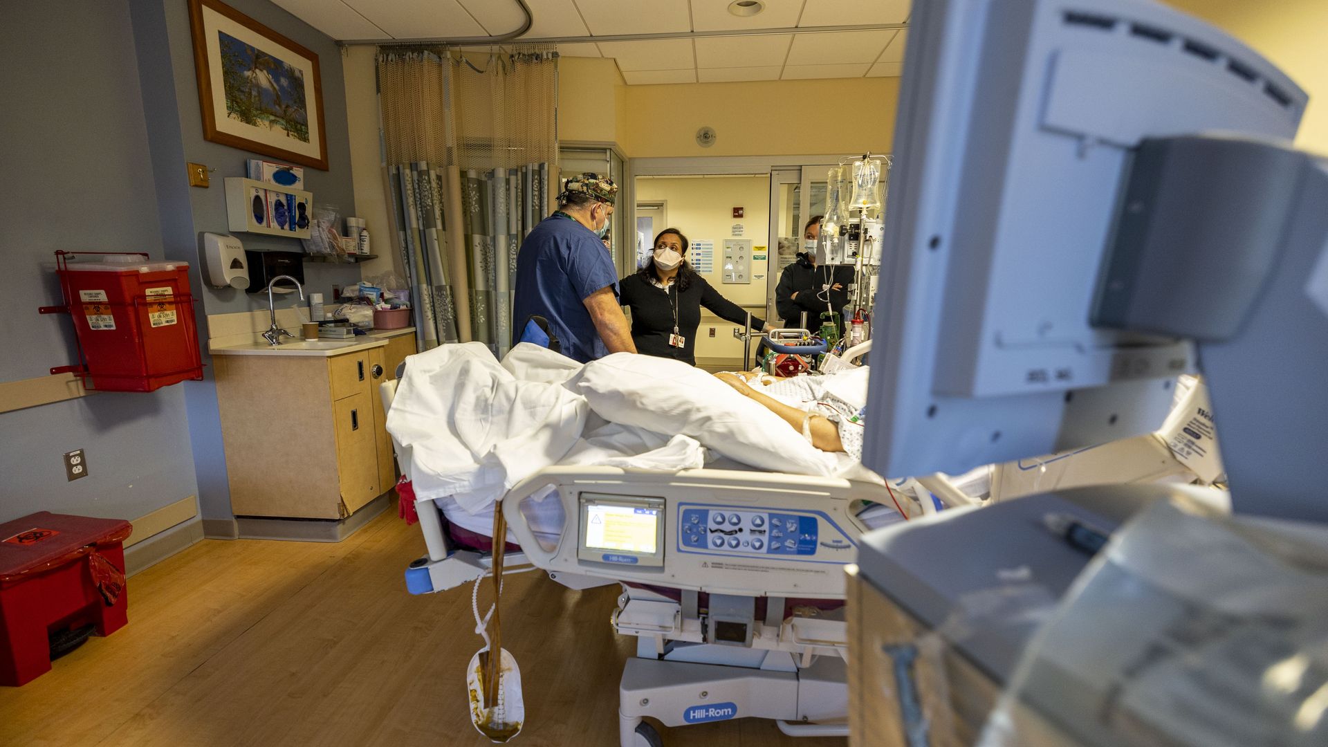 Photo of a doctor and a nurse standing next to a patient's bed at a hospital