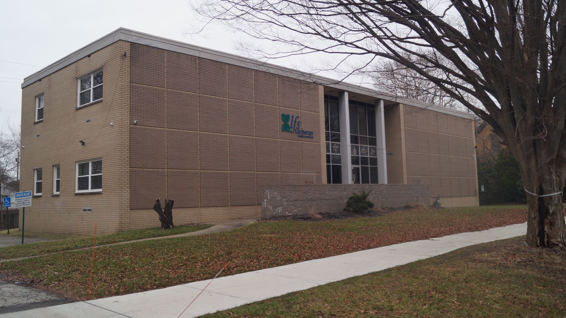 Beige brick building on a residential street in Cleveland, with a tree on the tree lawn.