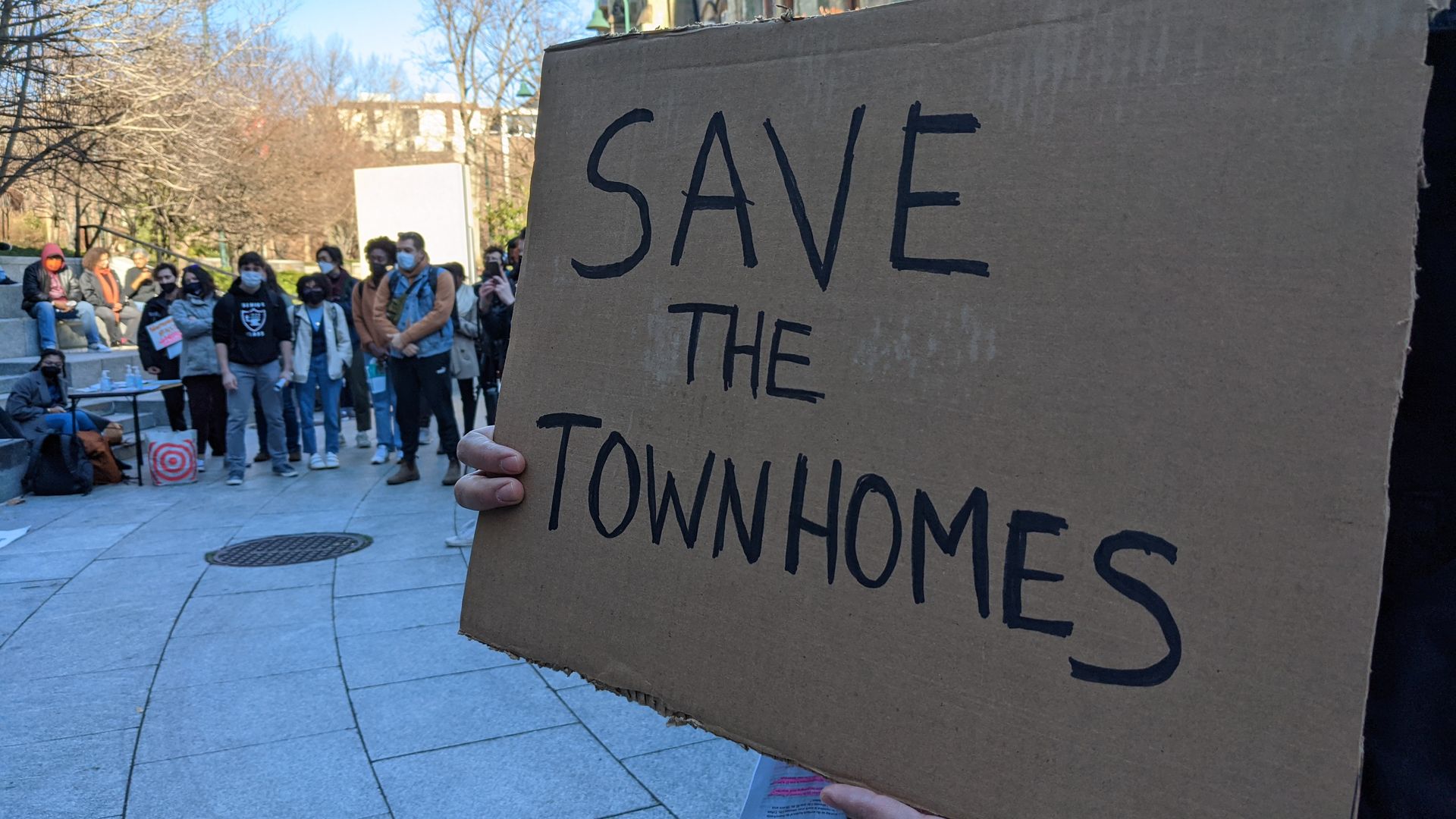 A demonstrator holding a sign saying to "Save the Townhomes."