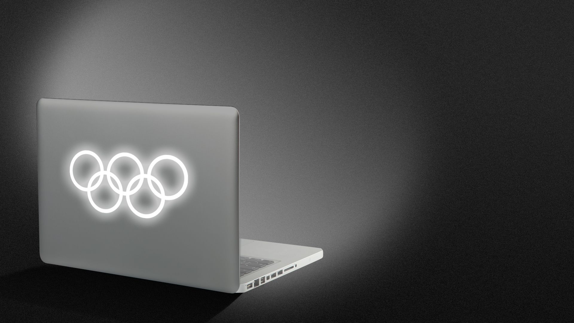 Illustration of the back of an opened laptop with the Olympic symbol as the glowing logo. 