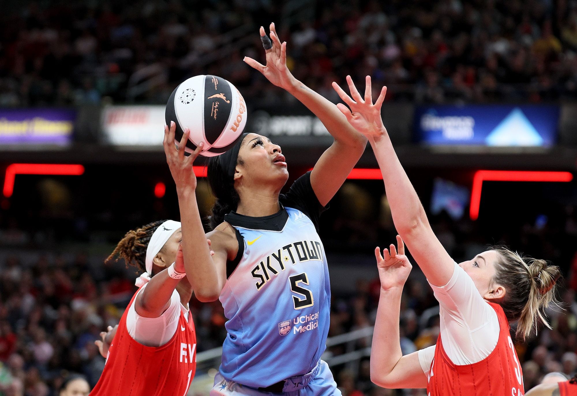 Angel Reese shooting a basket while two players defend her.