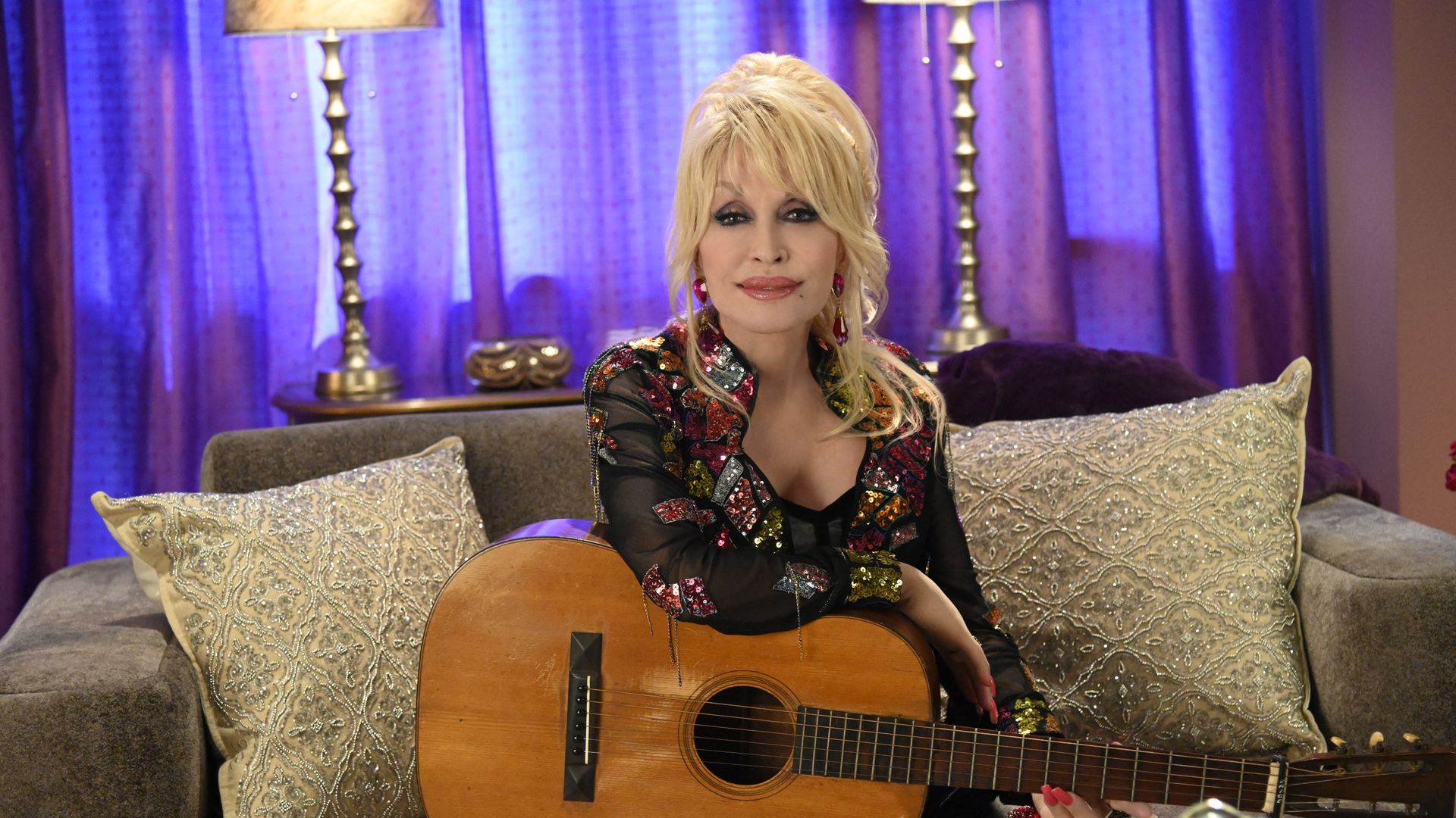  Dolly Parton sitting on a couch.
