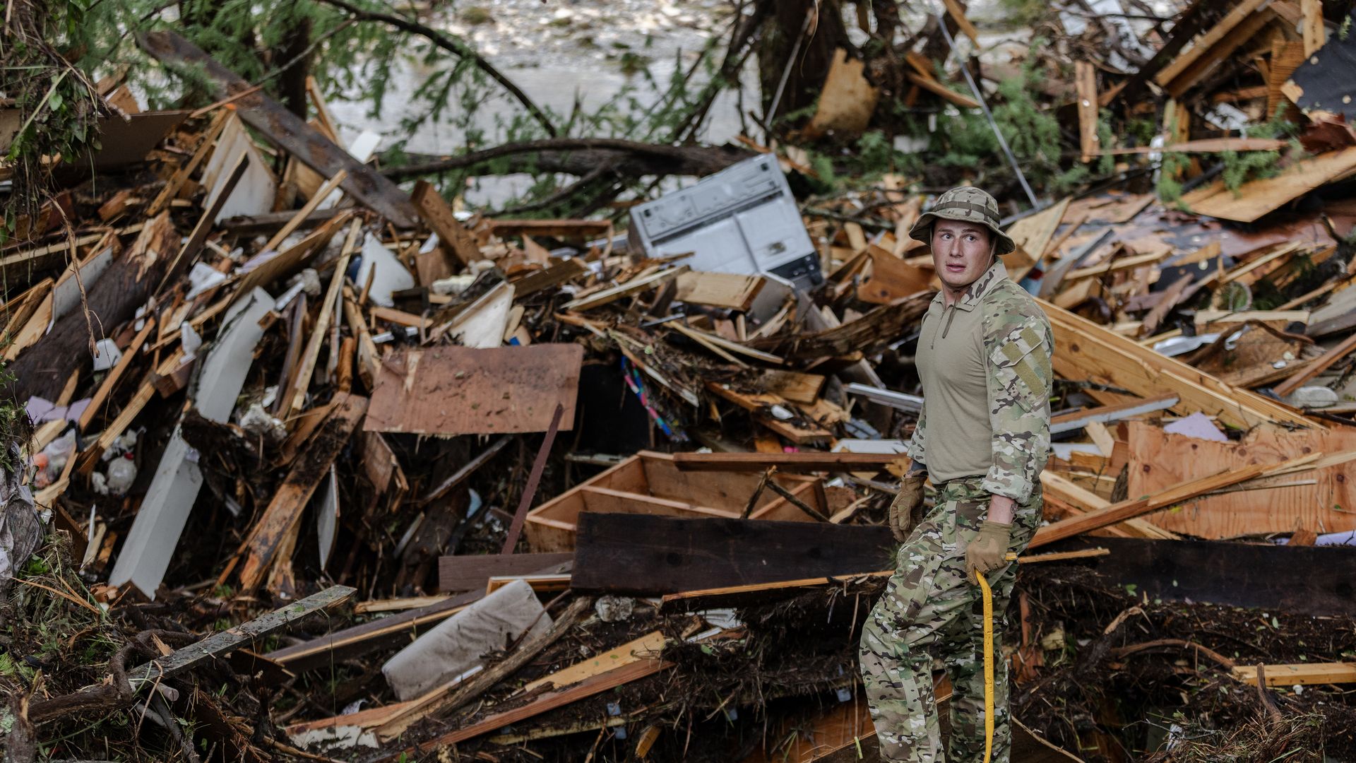 A person wearing camouflage clothing stands amid rubble after the Central Texas floods
