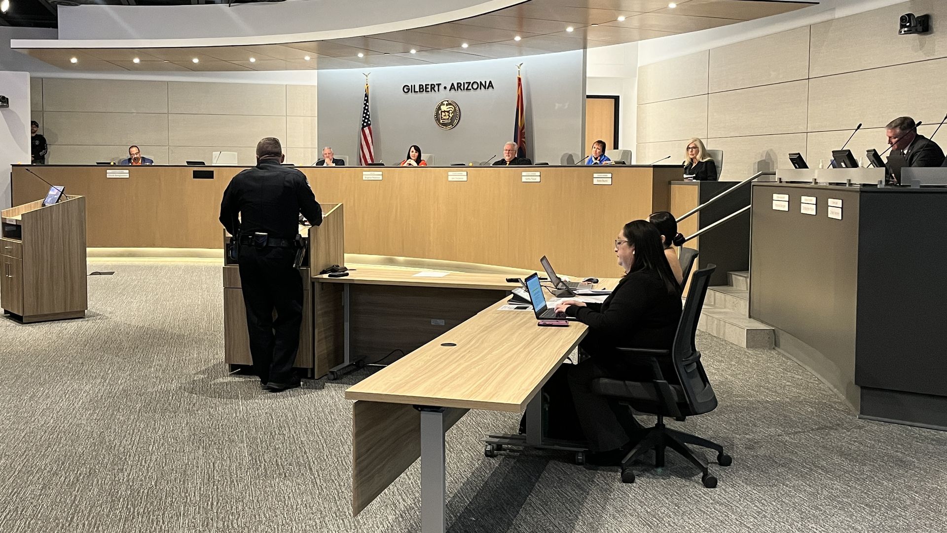 A police officer addressing people at a dais. 