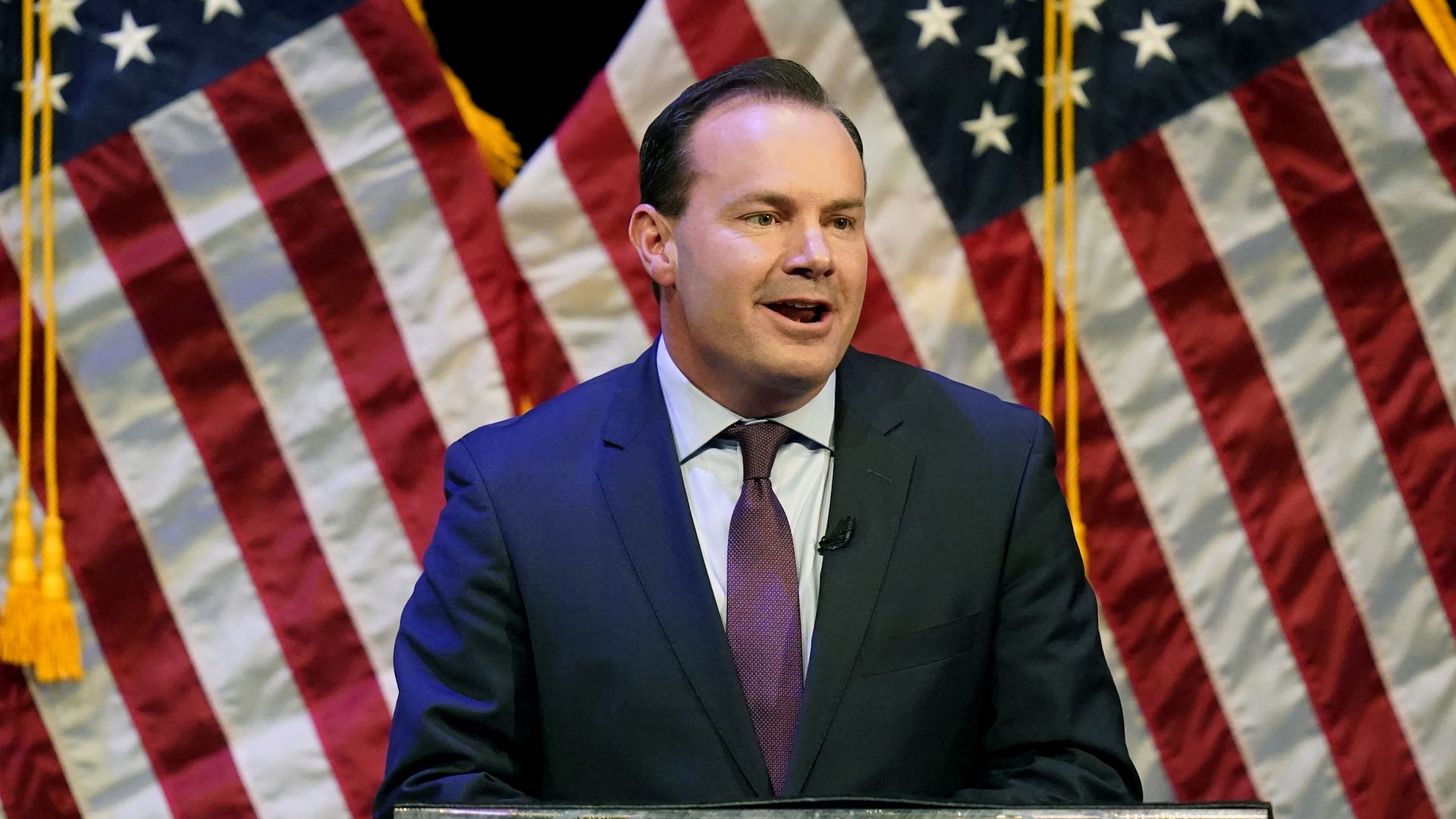 Mike Lee in front of American flags.
