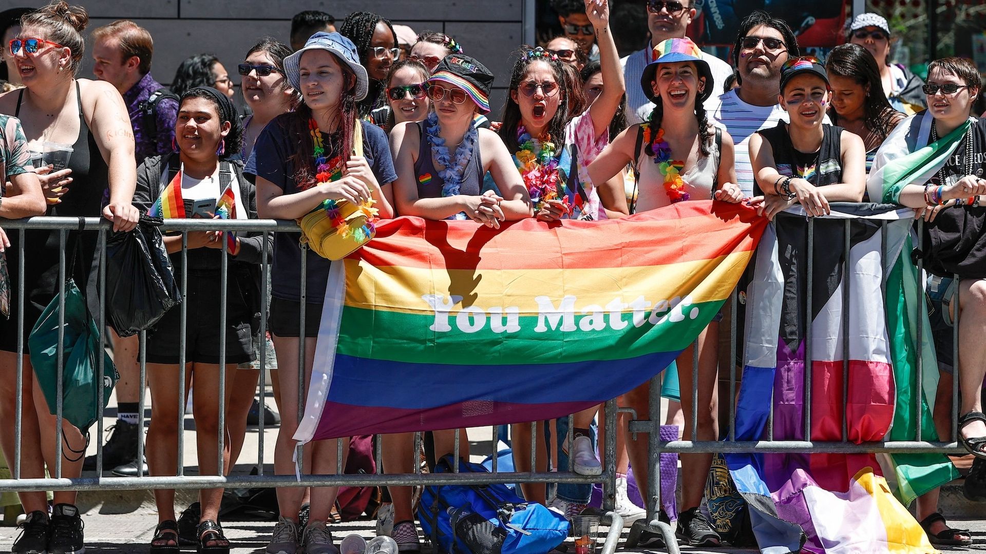 Photo of people watching a parade holding a flag that says "You Matter" 