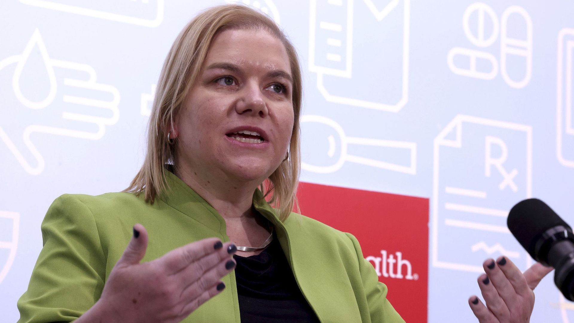 Photo of a woman talking in front of a microphone.