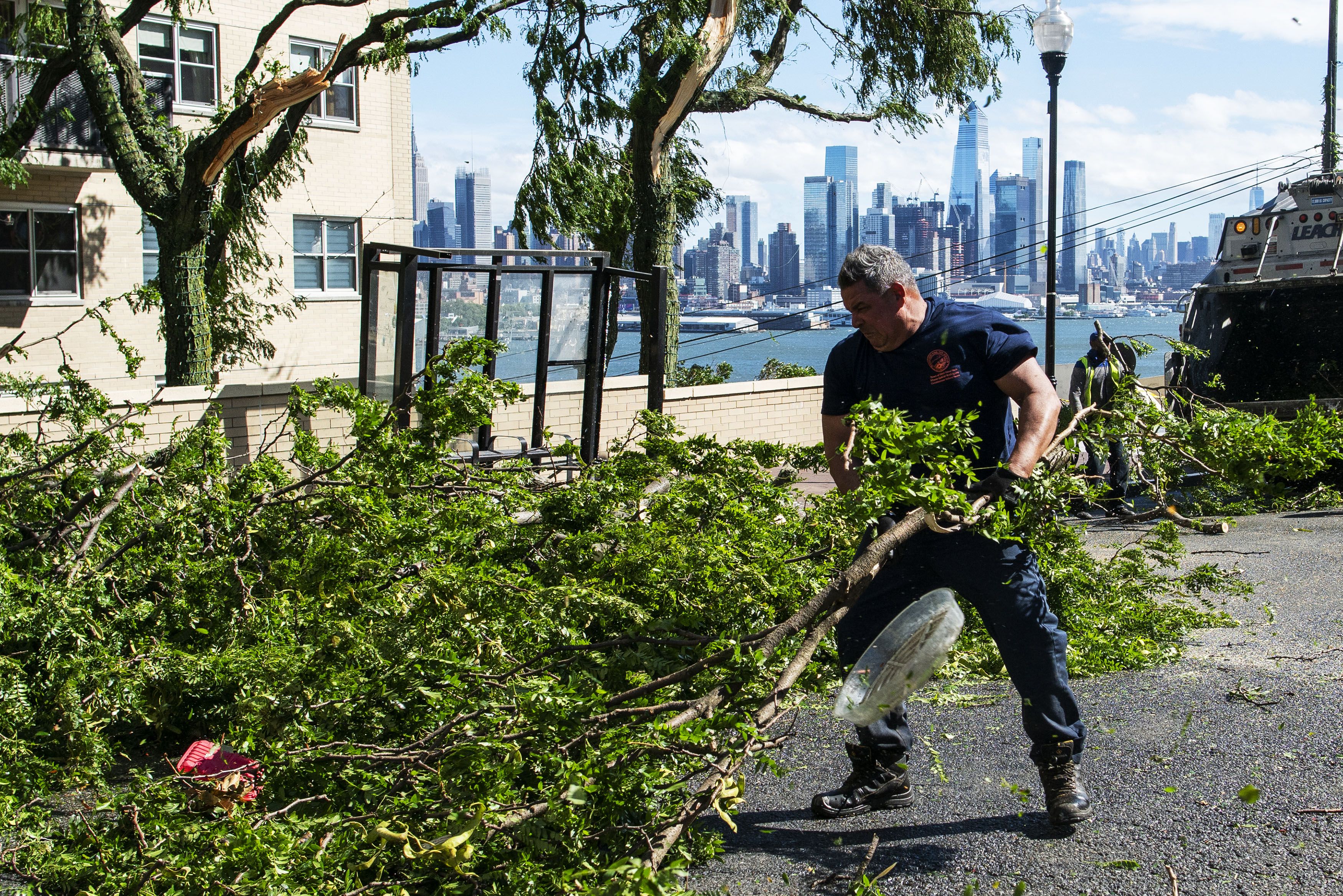 Workers clean the street of debris and branches after Tropical Storm Isaias passed through the region on August 4, 2020 in Guttenberg, New Jersey.