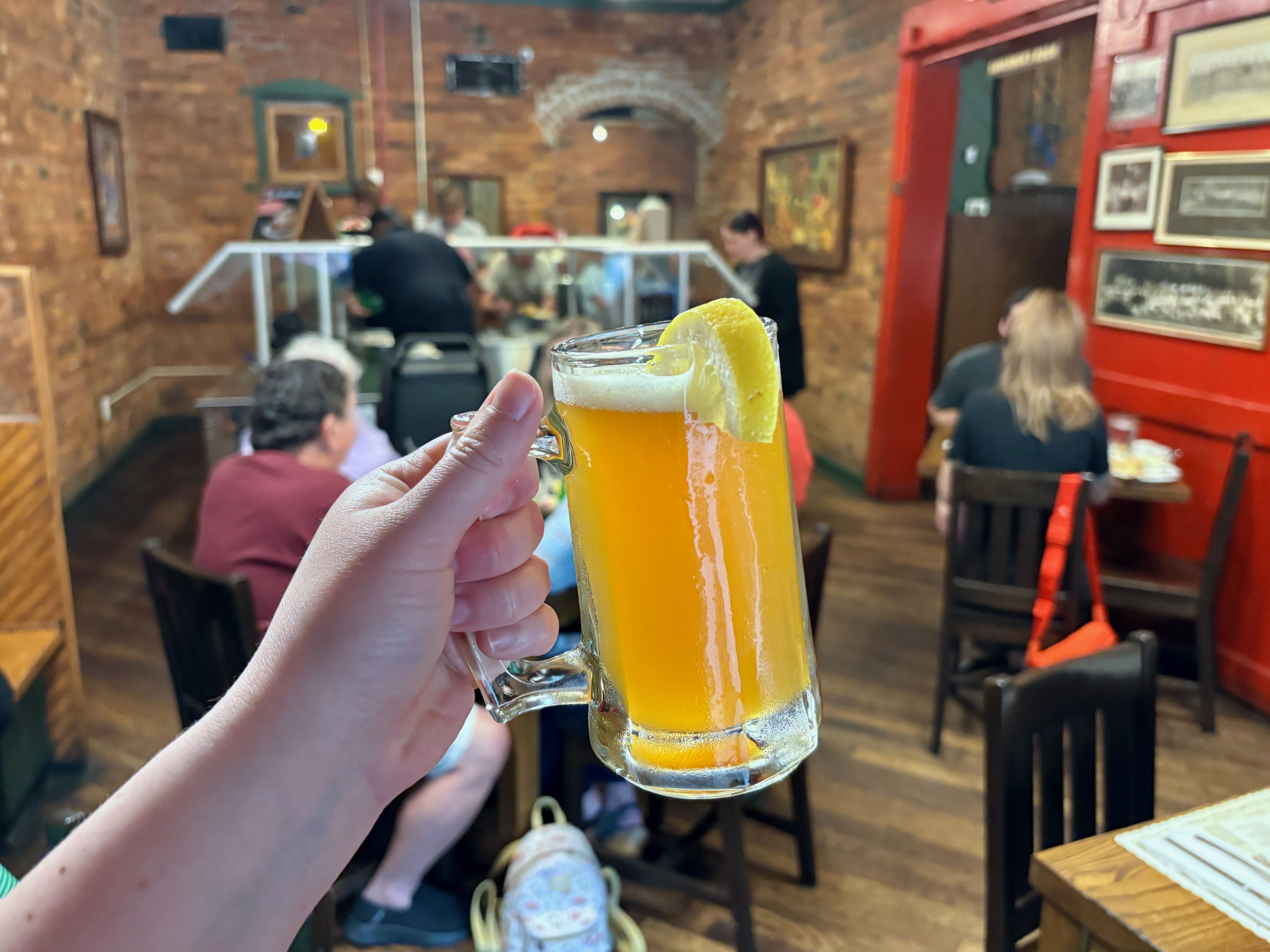 A close-up of Alissa's hand holding a full beer stein in front of the Schmidt's Autobahn buffet