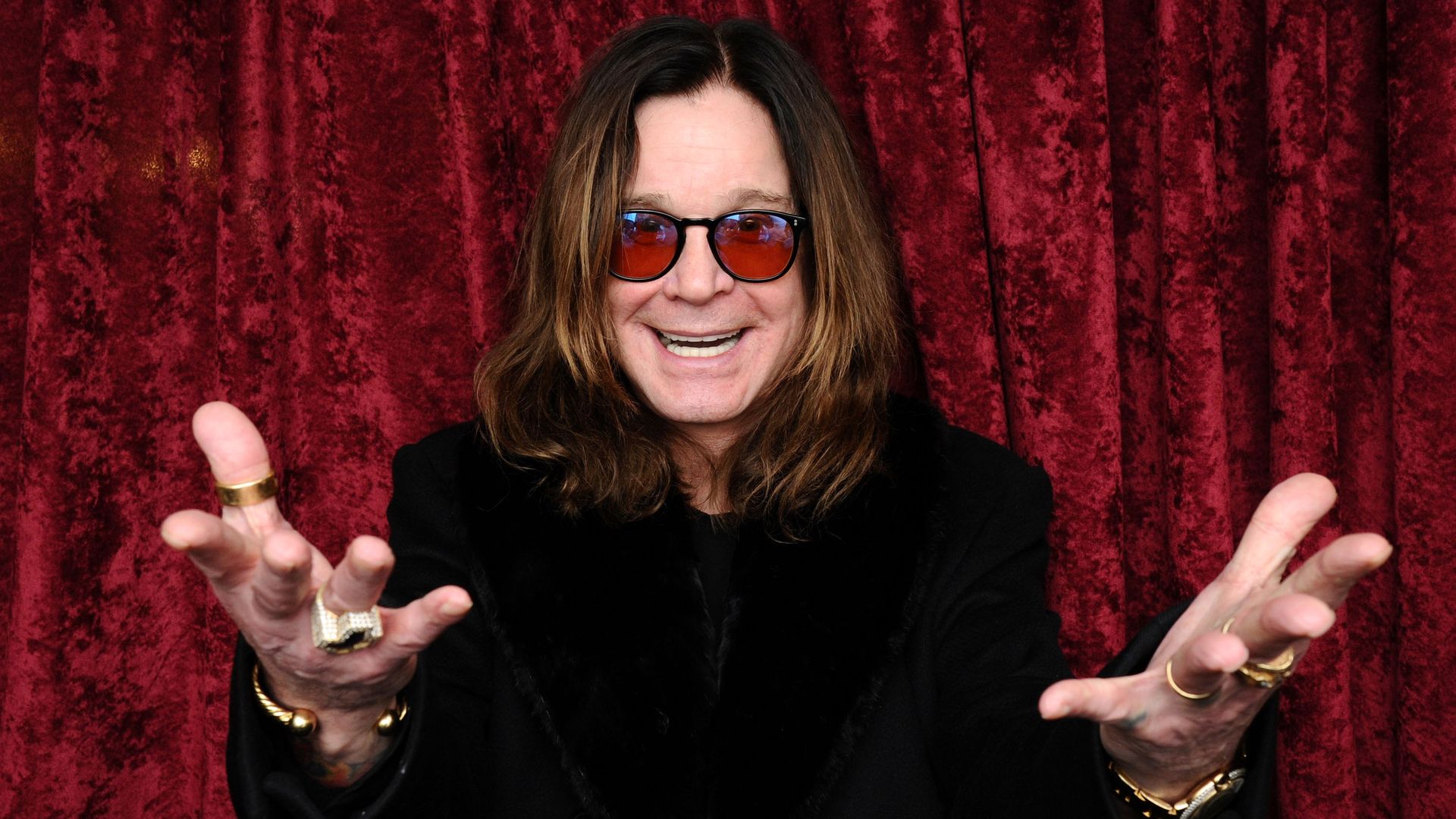 Ozzy Osbourne posses for a photo with his hands out.