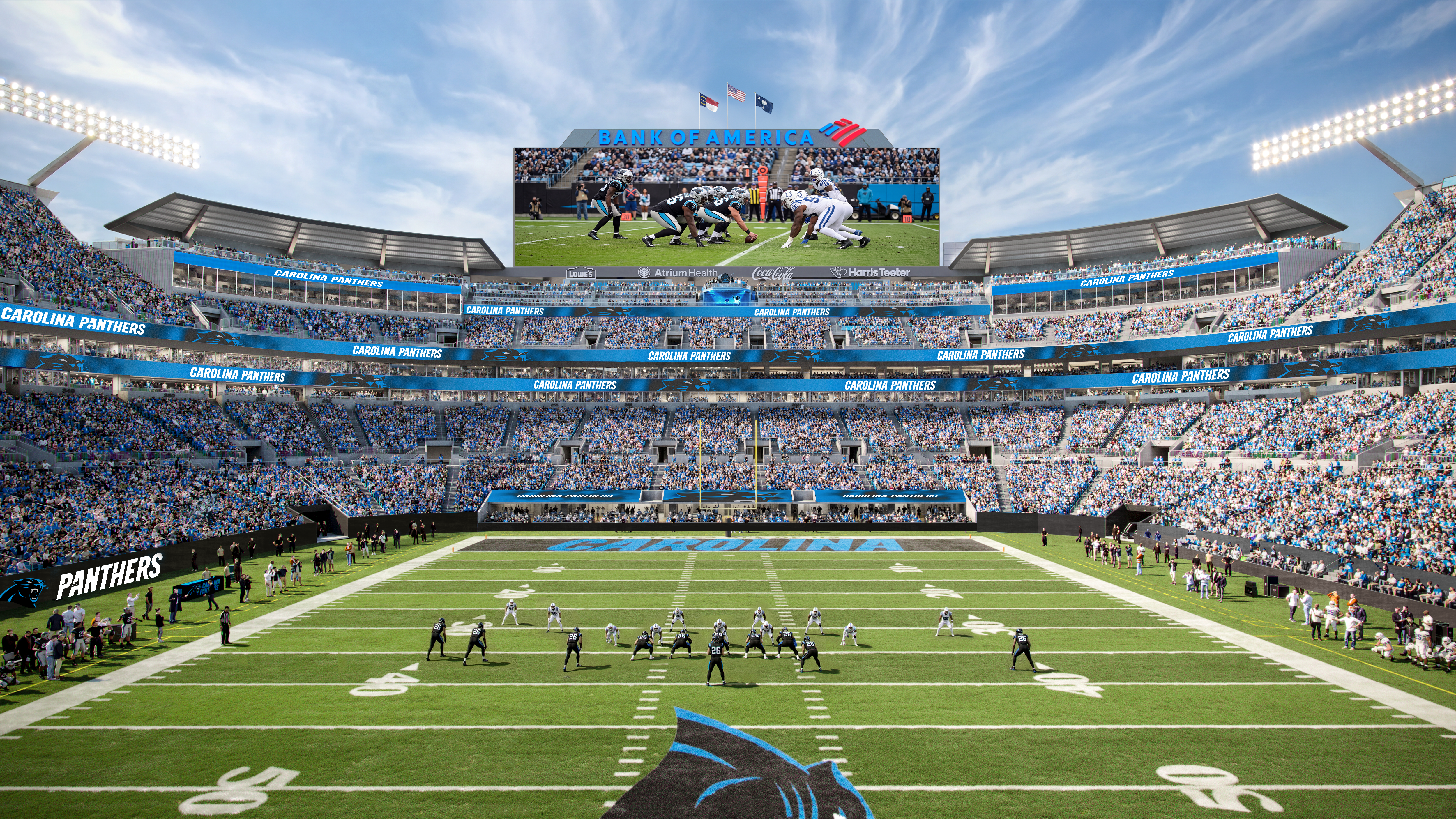 Panthers stadium full of fans under a blue sky. A large scoreboard shows a football play as players line up on the field; banners read CAROLINA PANTHERS.