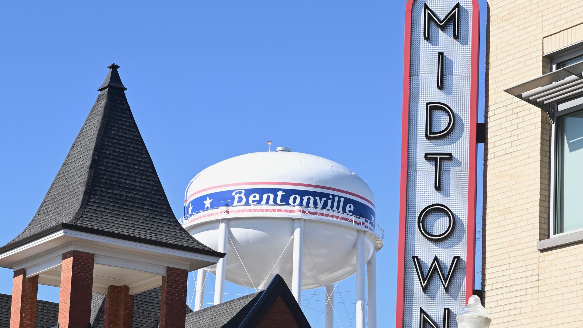 A photo of Bentonville, Arkansas' water tower, near a church bell tower.