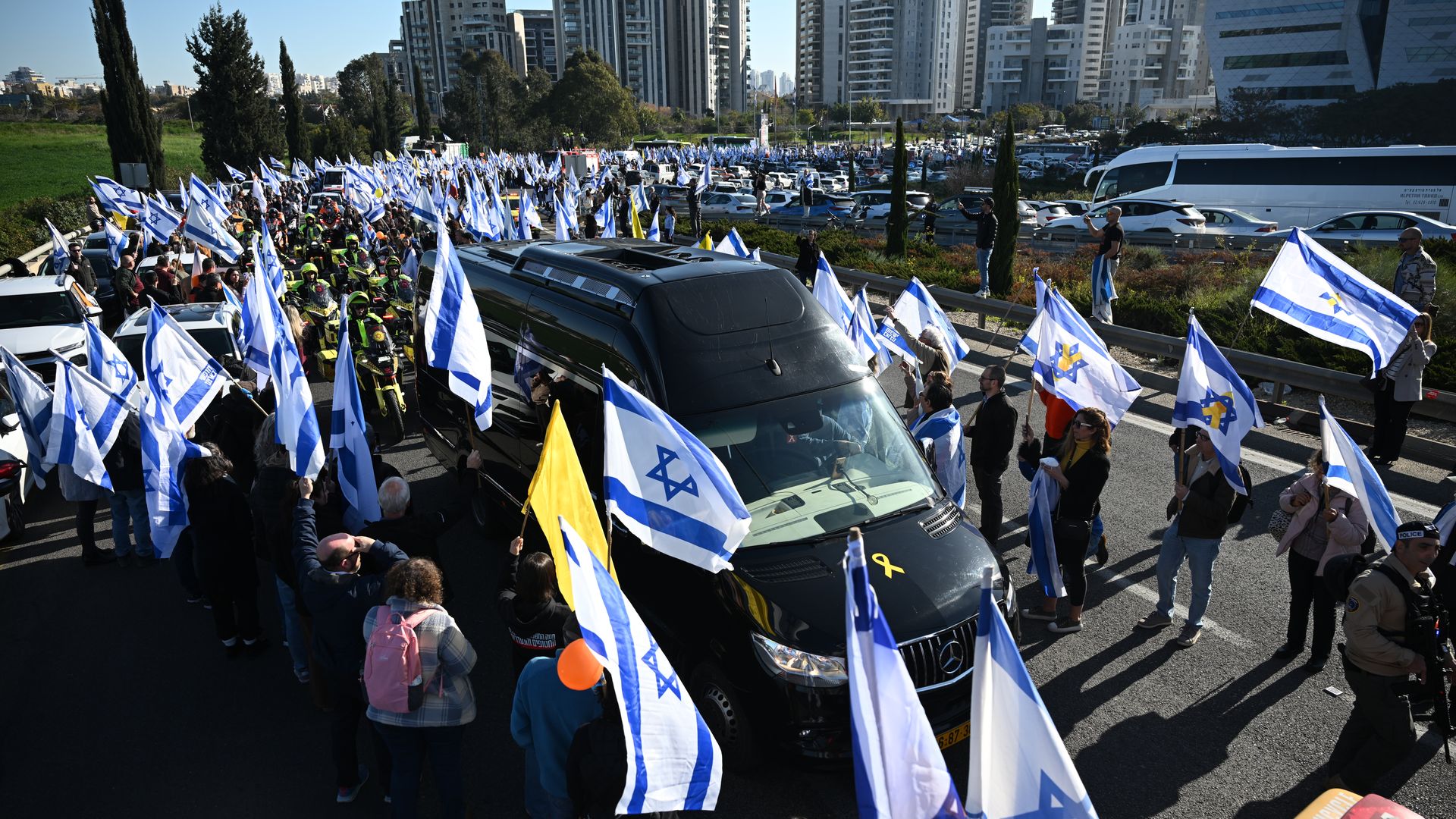 People line the street to watch the funeral procession carrying the caskets of Shiri Bibas, Kfir Bibas and Ariel Bibas, with family in minibuses, on Wednesday in Rishon LeZion, Israel. 