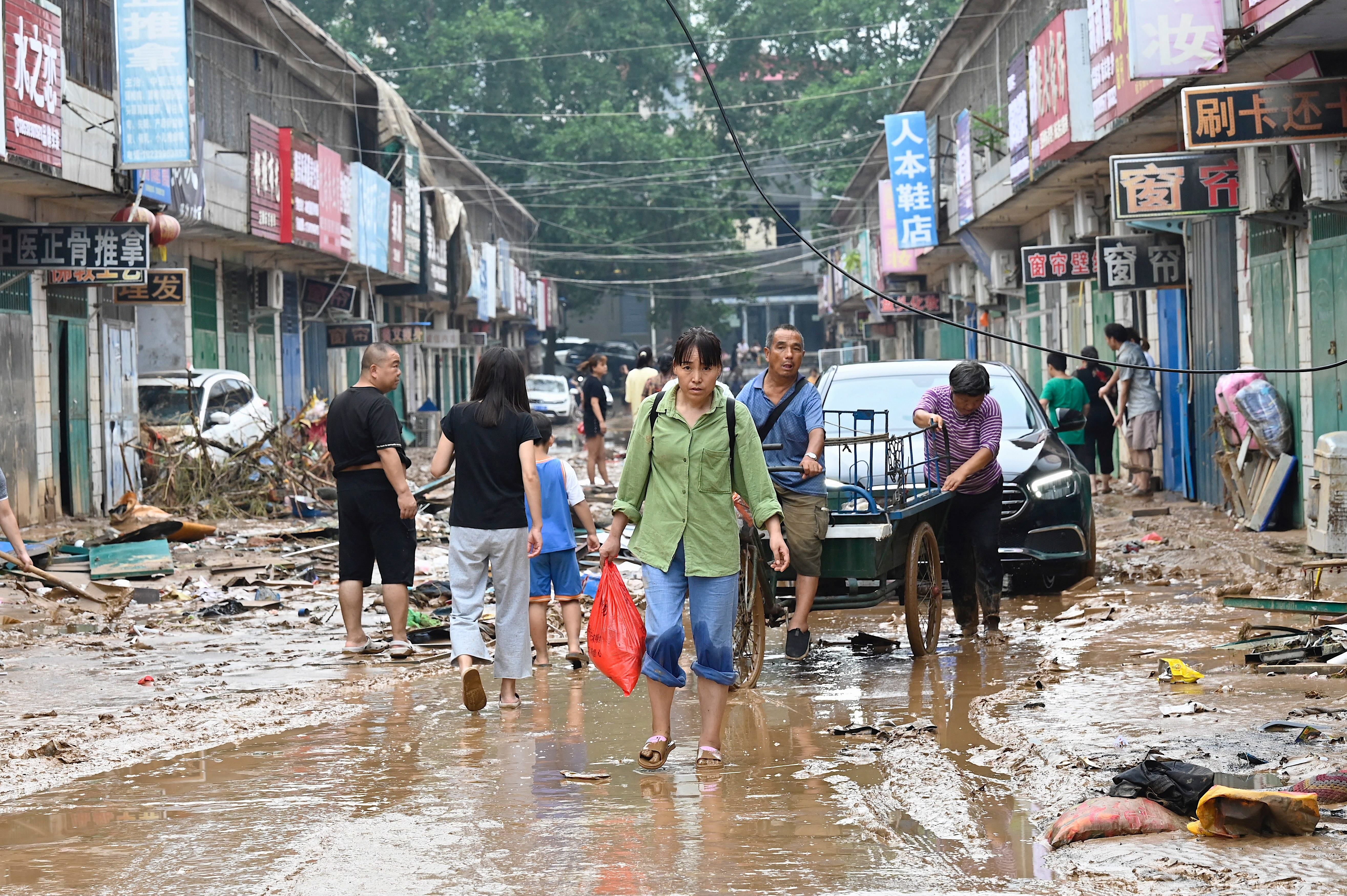 A person carrying a bag through a flooded street in Gongyi city on July 22.