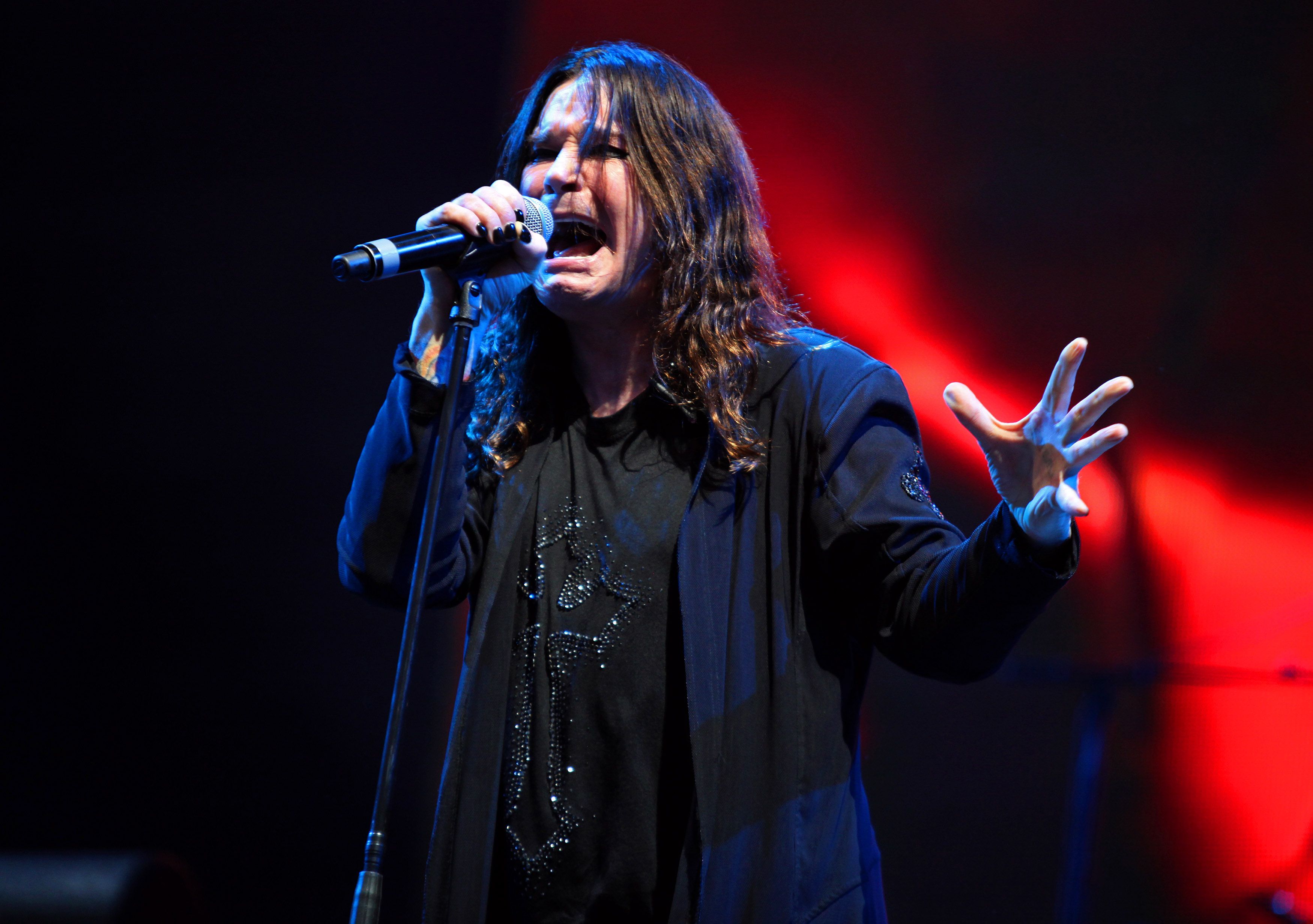 Photo of a man with long hair singing into a microphone during a song.