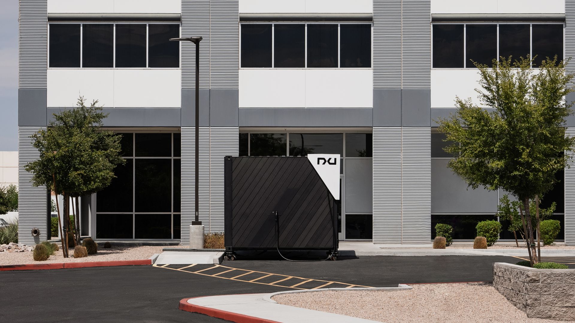 An electrical vehicle charger outside an office building.